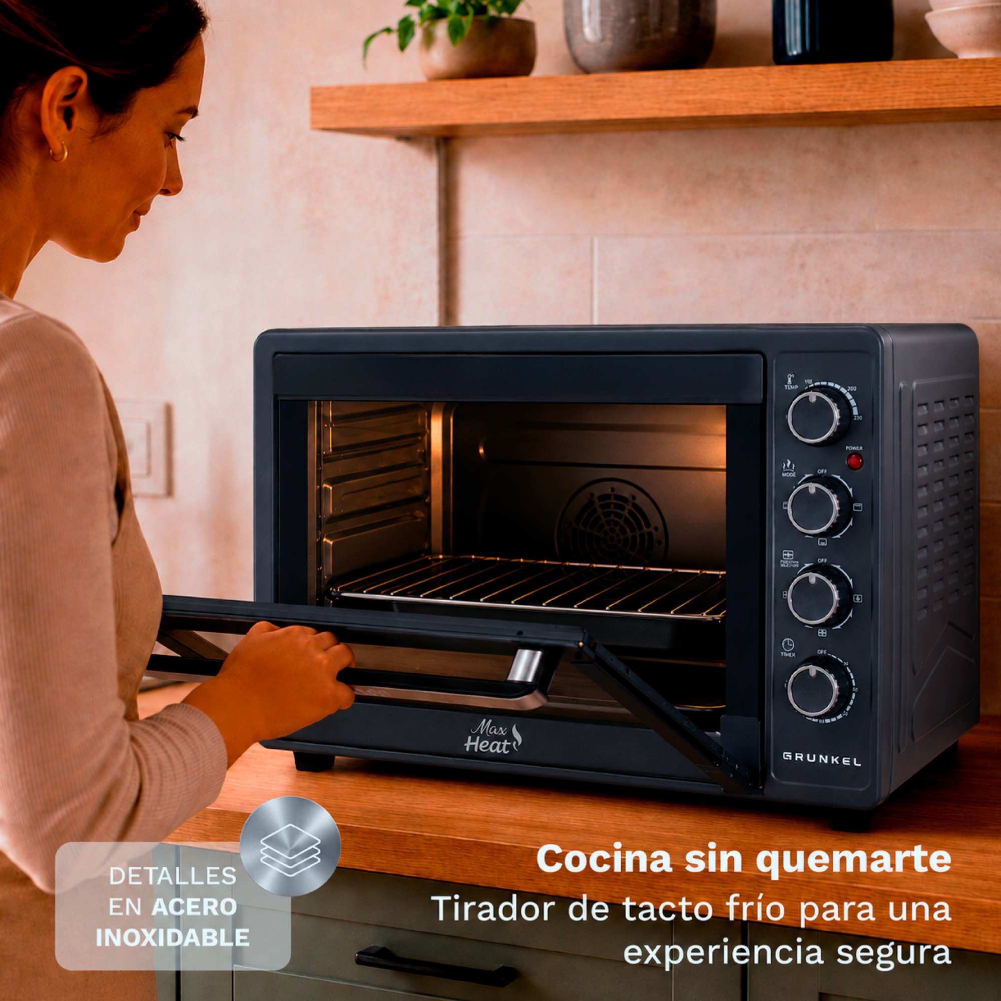 Mujer abriendo la puerta de un mini horno negro Grunkel Max Heat en una encimera de madera.