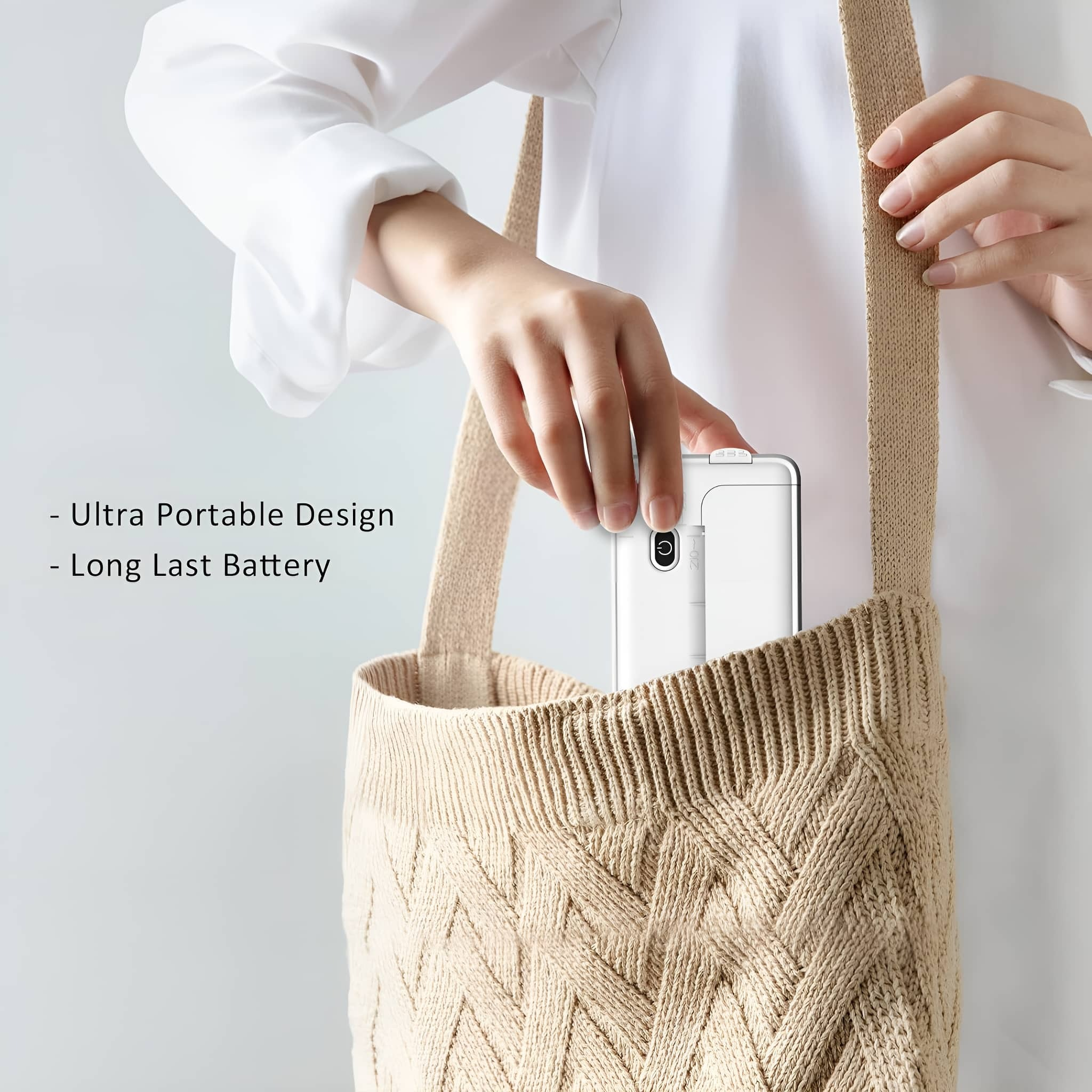 Eine Person legt ein weißes tragbares Gerät in eine beige Stricktasche vor weißem Hintergrund.