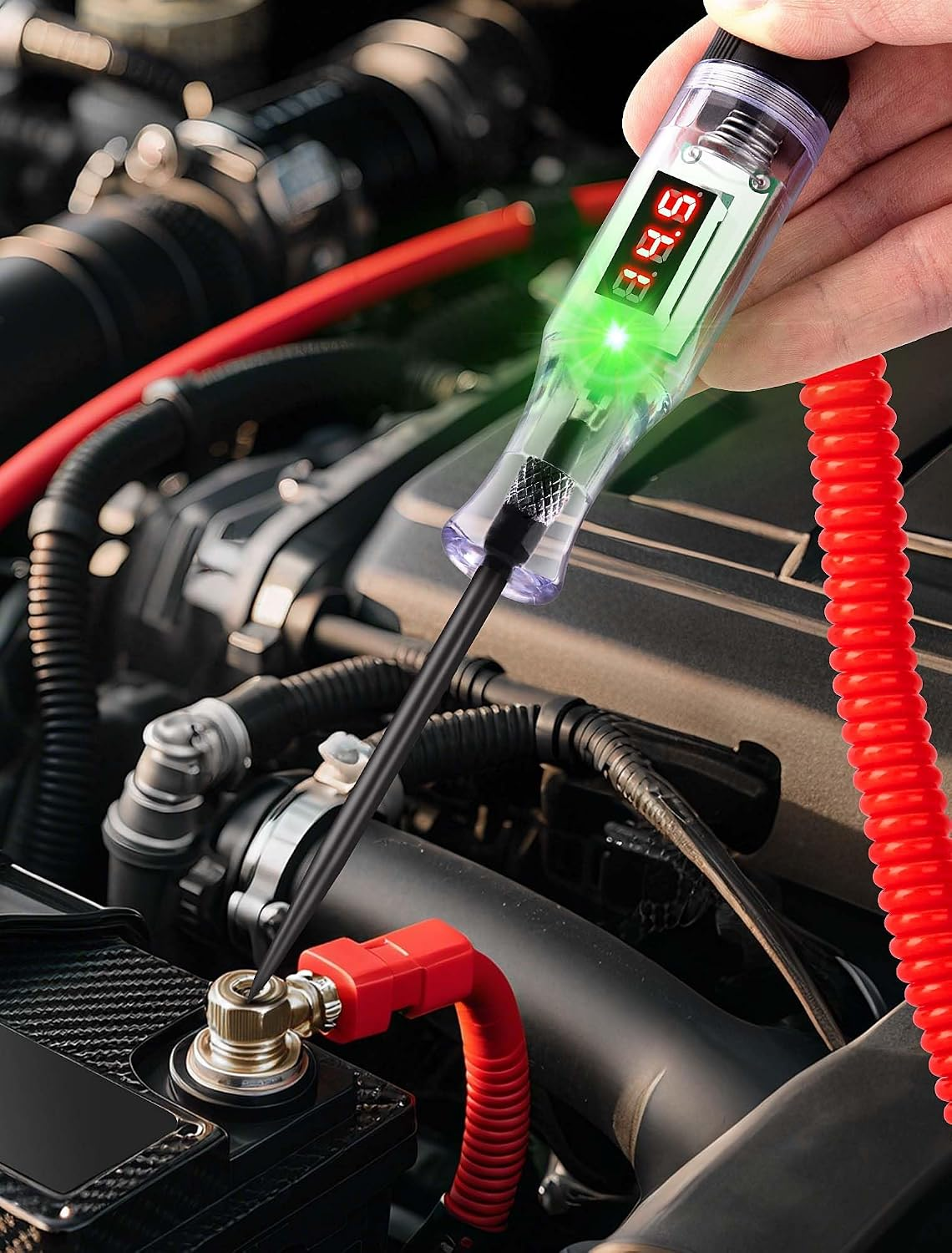 Hand hält einen digitalen Spannungsprüfer mit grünem Licht an einer Autobatterie.