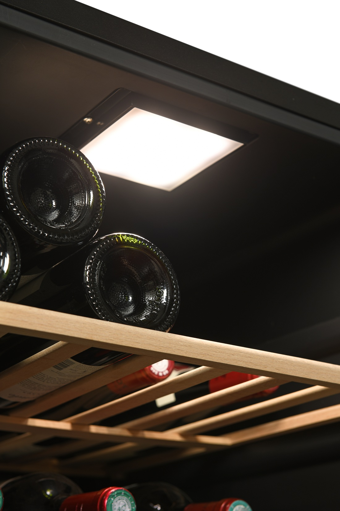 Botellas de vino en un estante de madera dentro de una vinoteca con luz cenital.