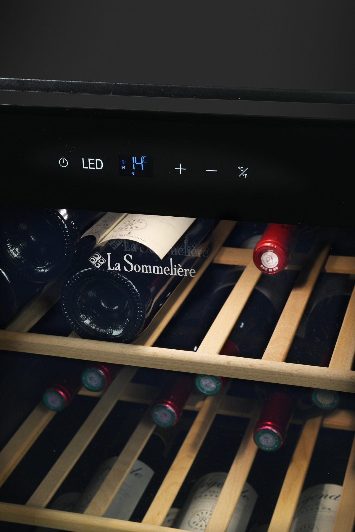 Frigorífico para vinos con pantalla LED iluminada a 14 grados, lleno de estantes de madera y botellas.