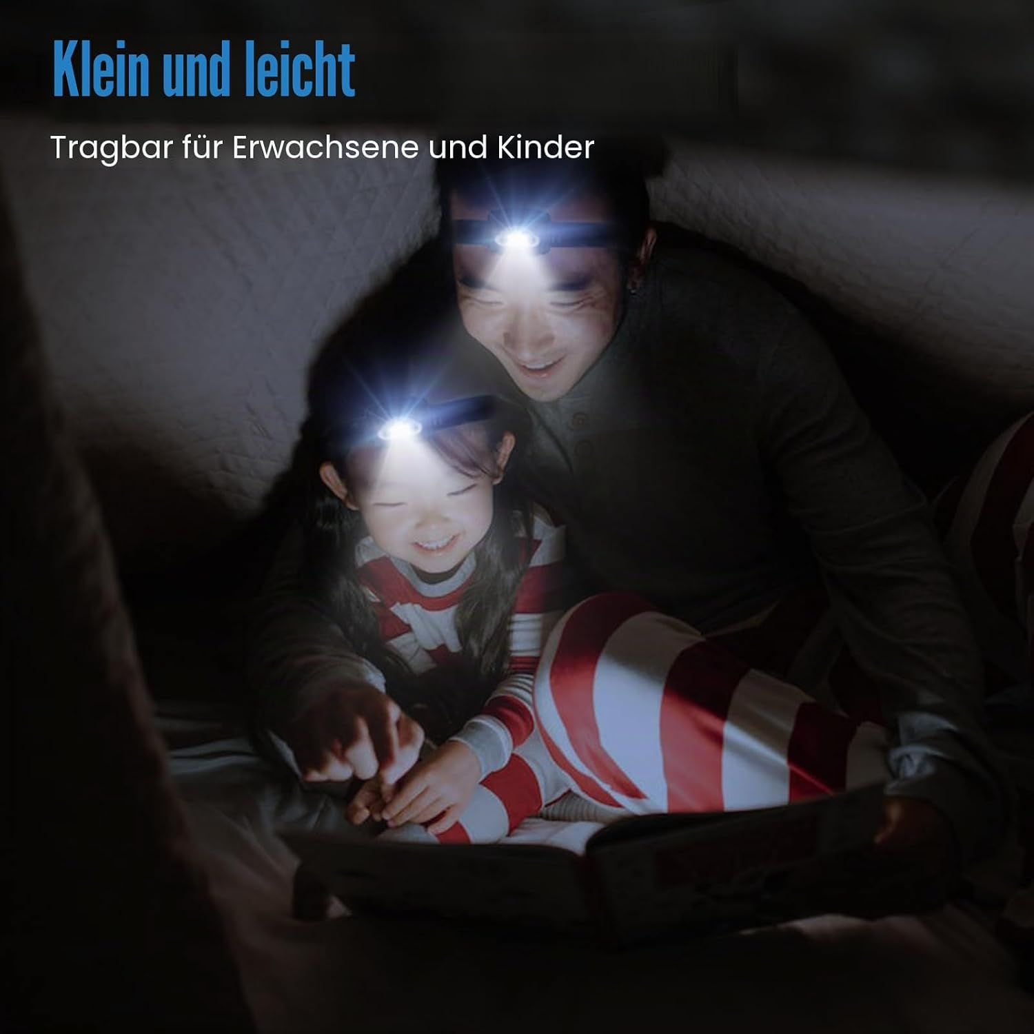 Ein Vater und seine Tochter lesen im Zelt mit Stirnlampen.