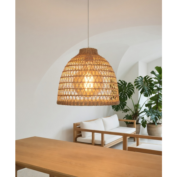 Una lámpara colgante de ratán cuelga sobre una mesa de madera, con un sofá y plantas al fondo.
