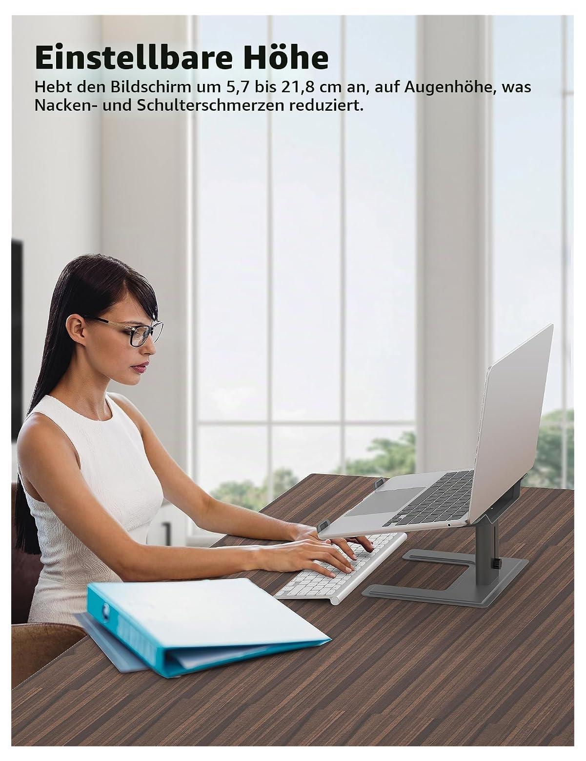 Eine Frau arbeitet an einem Laptop, der auf einem verstellbaren grauen Ständer auf einem Holzschreibtisch steht.