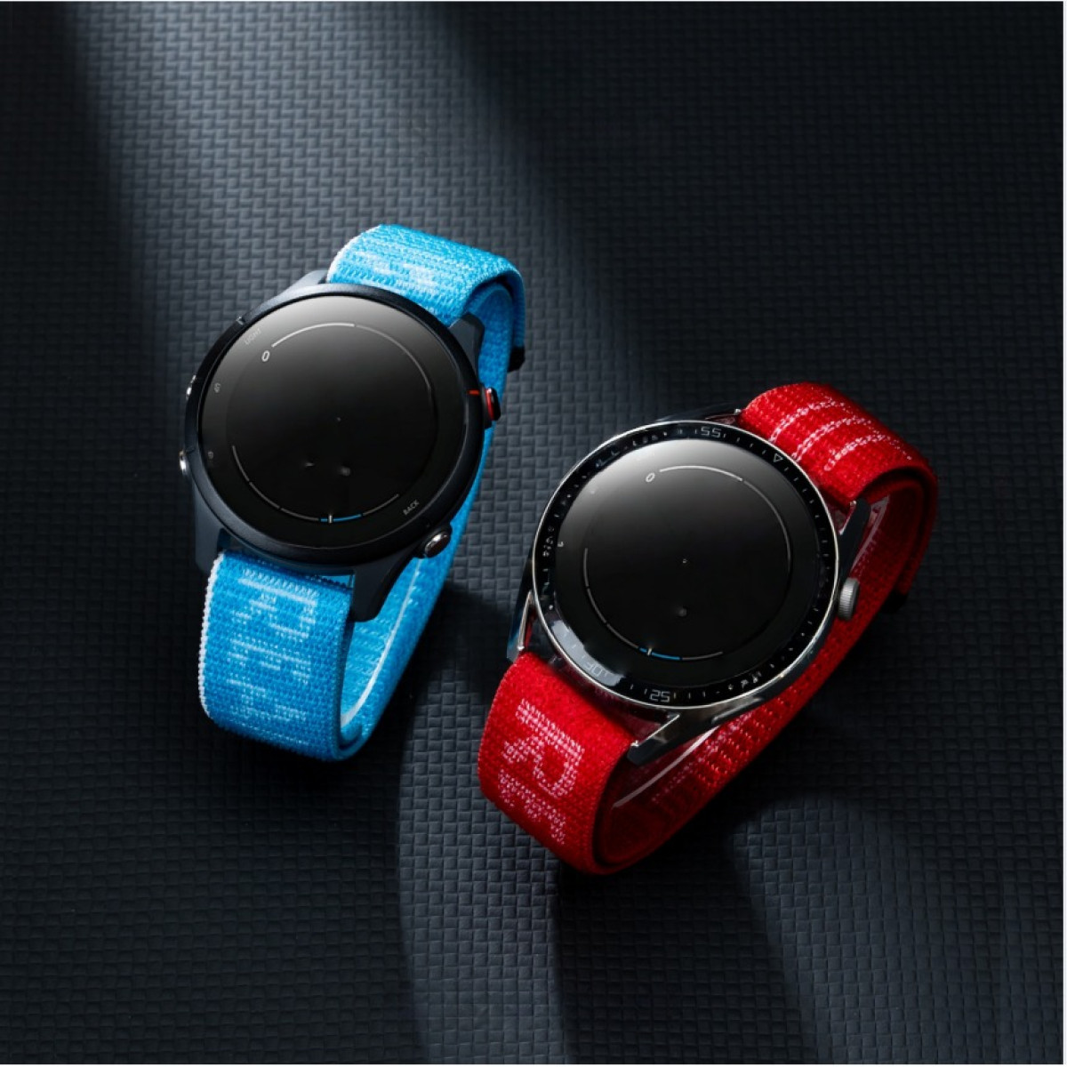 Zwei Smartwatches mit Stoffarmbändern, eine blau, die andere rot, auf schwarzem Hintergrund.