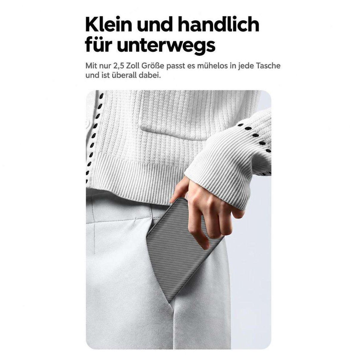 Eine Hand schiebt ein kompaktes graues Gerät in die Hosentasche, im Hintergrund Text und helle Kleidung.