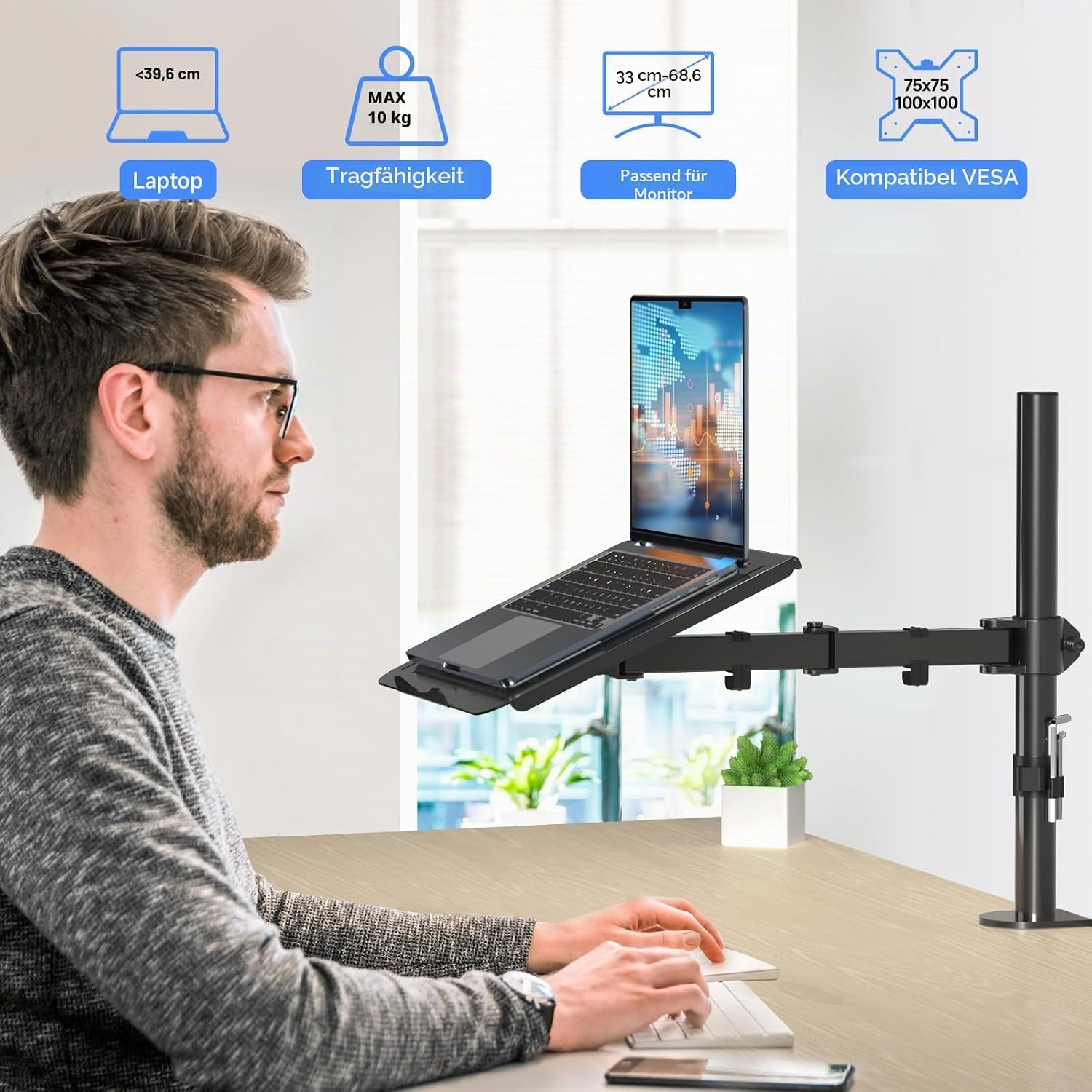 Ein Mann sitzt an einem Holztisch, vor ihm ist ein Laptop an einem verstellbaren Arm befestigt.