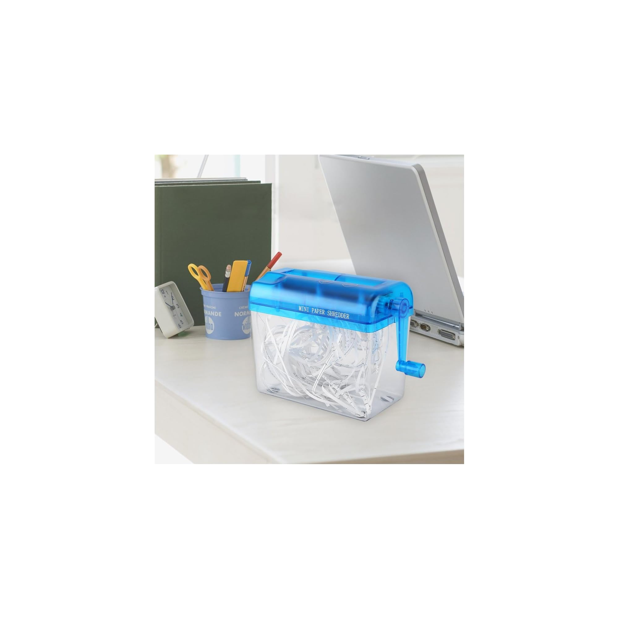 Ein blauer manueller Mini-Aktenvernichter steht auf einem Schreibtisch mit zerkleinertem Papier im transparenten Behälter.