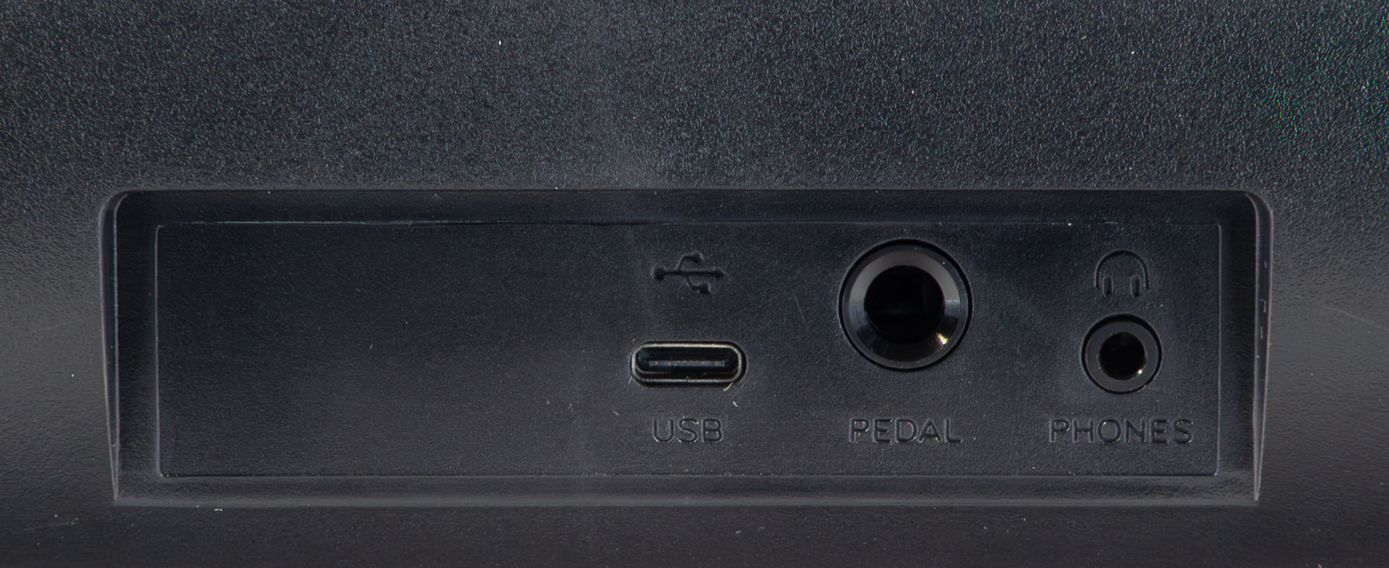Rückseite eines schwarzen Geräts mit USB-, Pedal- und Kopfhöreranschlüssen.