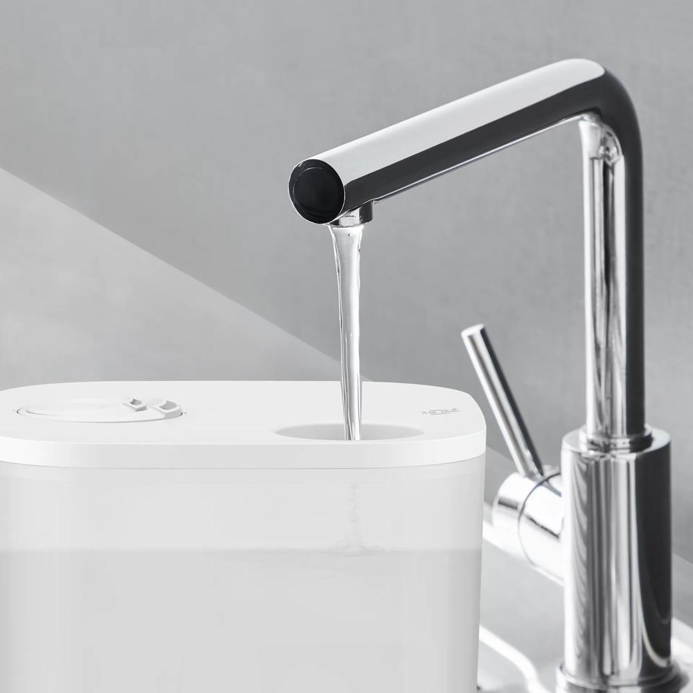 Ein chromfarbener Wasserhahn gießt klares Wasser in einen weißen Behälter.
