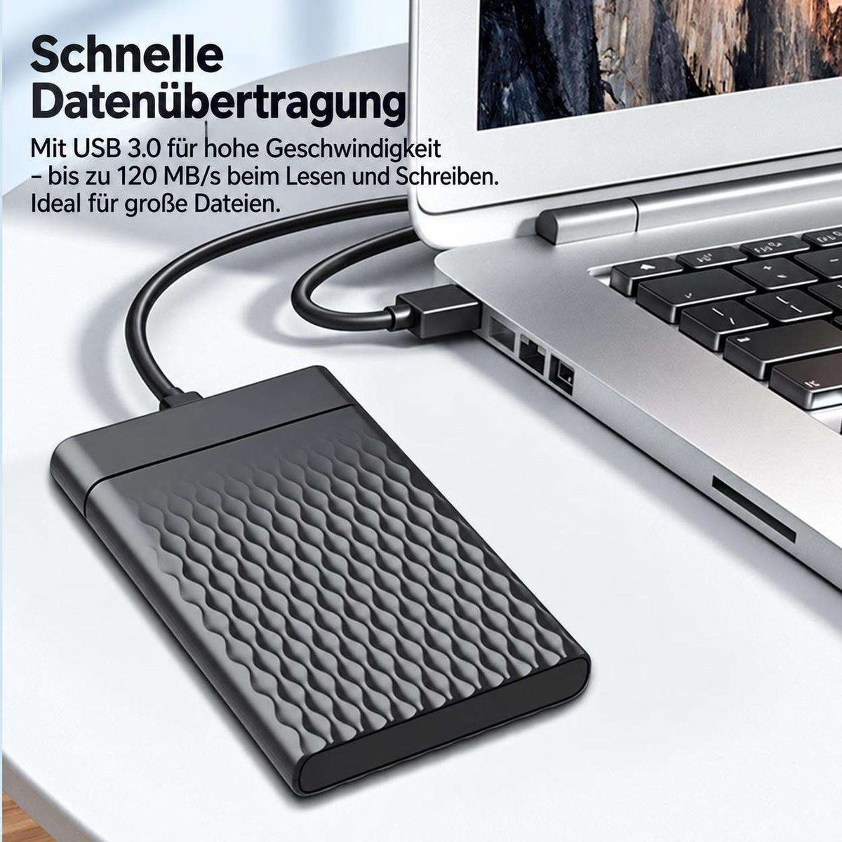 Eine externe schwarze Festplatte mit Wellenmuster ist per USB-Kabel an einen silbernen Laptop angeschlossen.