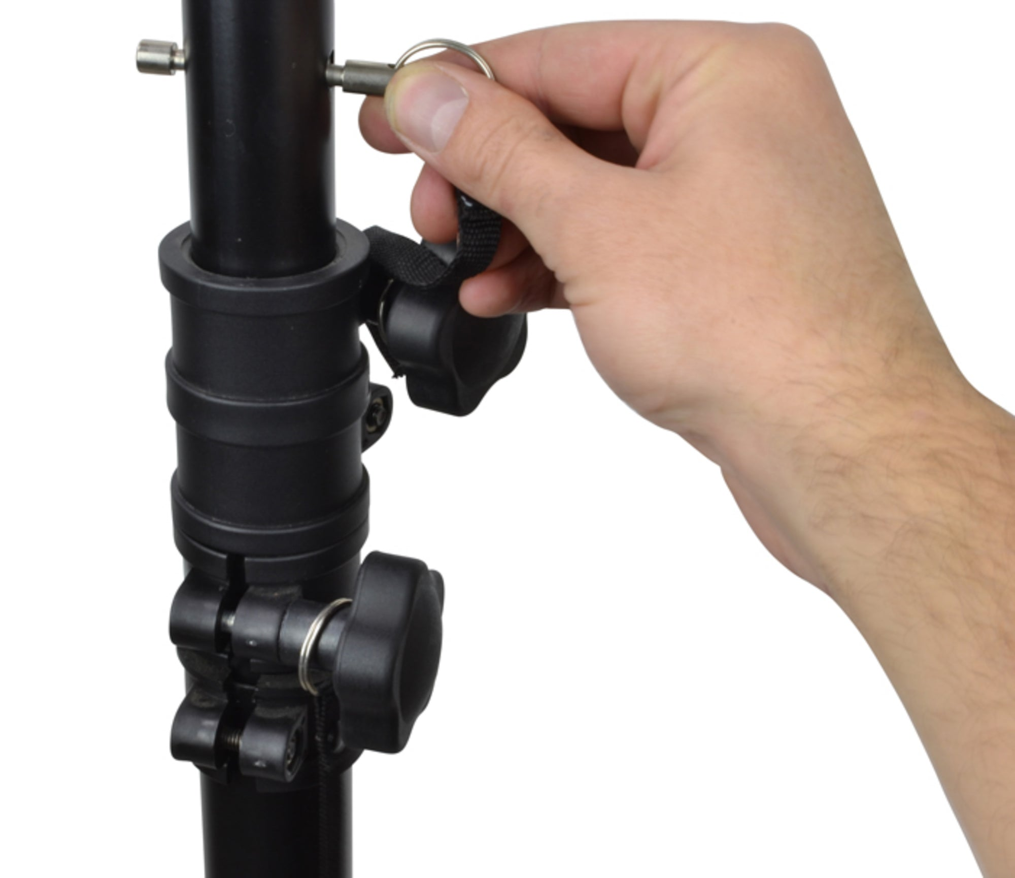 Eine Hand zieht den Metallstift heraus, um ein schwarzes Stativ einzustellen.
