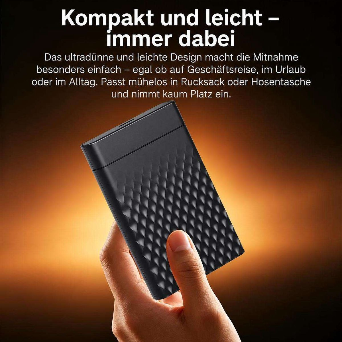 Eine Hand hält eine kompakte, schwarze externe Festplatte mit strukturiertem Muster vor einem warmen Hintergrund.