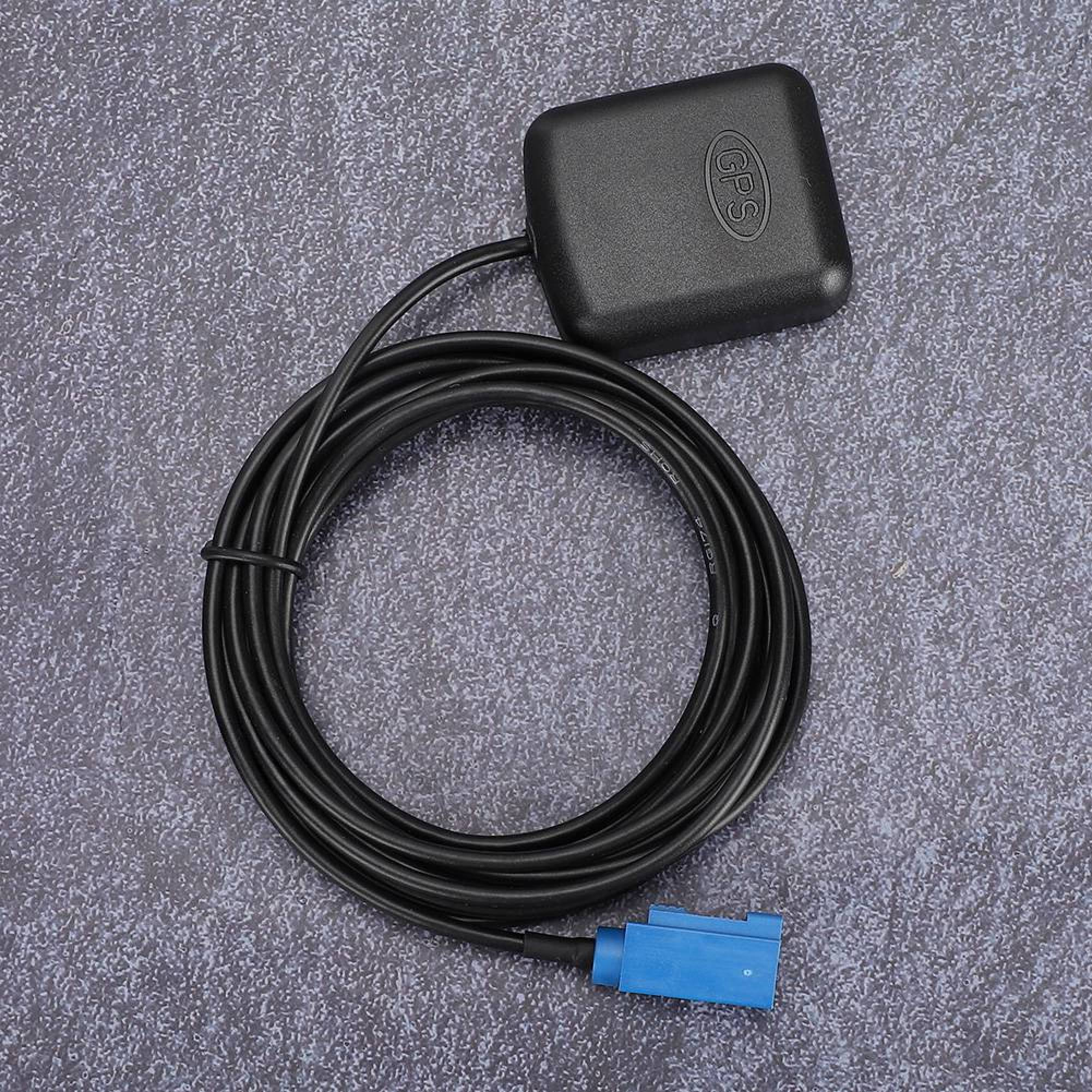 Schwarze GPS-Antenne mit aufgerolltem Kabel und blauem Stecker auf grauem Untergrund.
