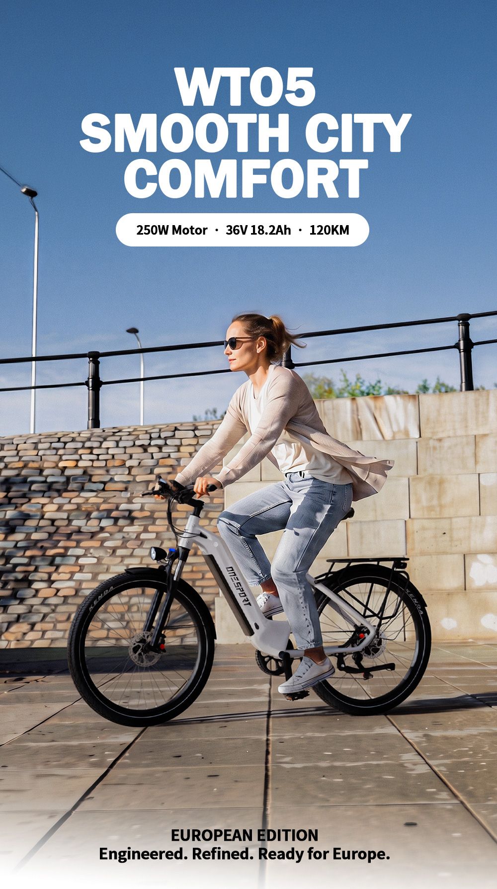 Una donna bionda guida una bicicletta elettrica bianca davanti a un muro di pietra sotto il cielo azzurro.