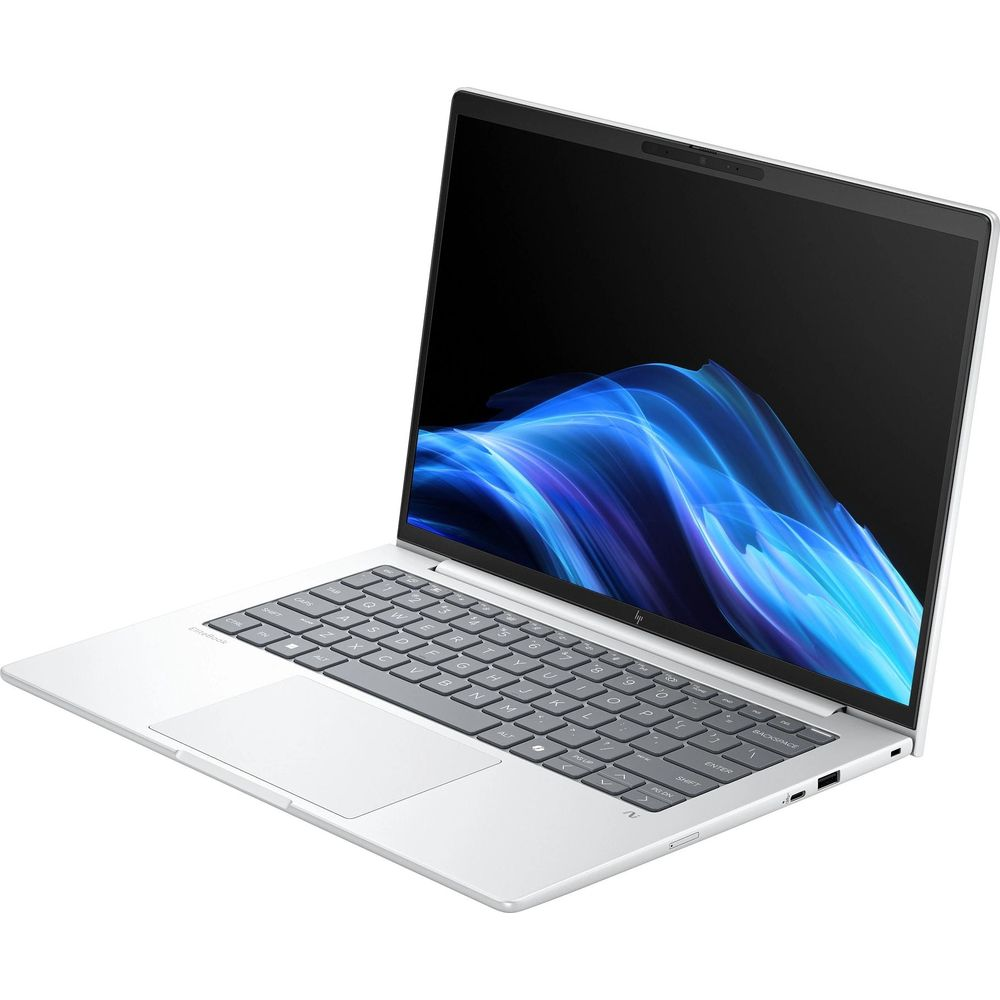 Un laptop argentato con tastiera grigia e sfondo a onde blu sullo schermo, su sfondo bianco.