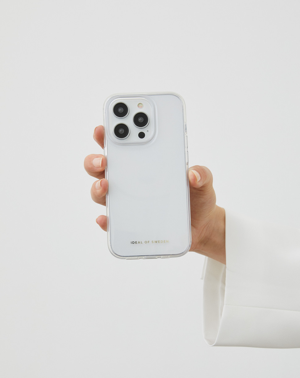 Eine Hand in einem weißen Hemd hält ein Smartphone mit klarer Hülle vor weißem Hintergrund.