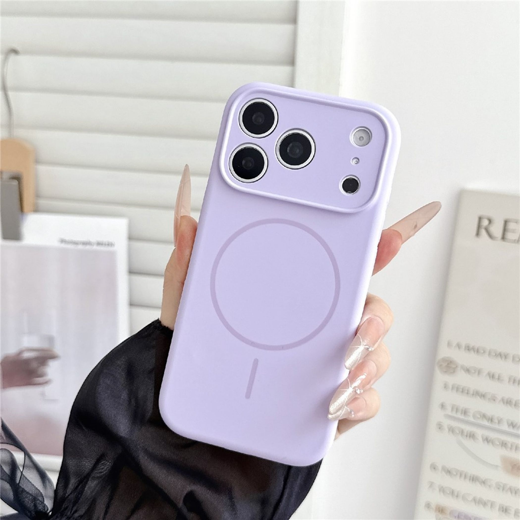Eine Hand hält eine lila Smartphone-Hülle mit einem runden Ring und dreifacher Kamera.