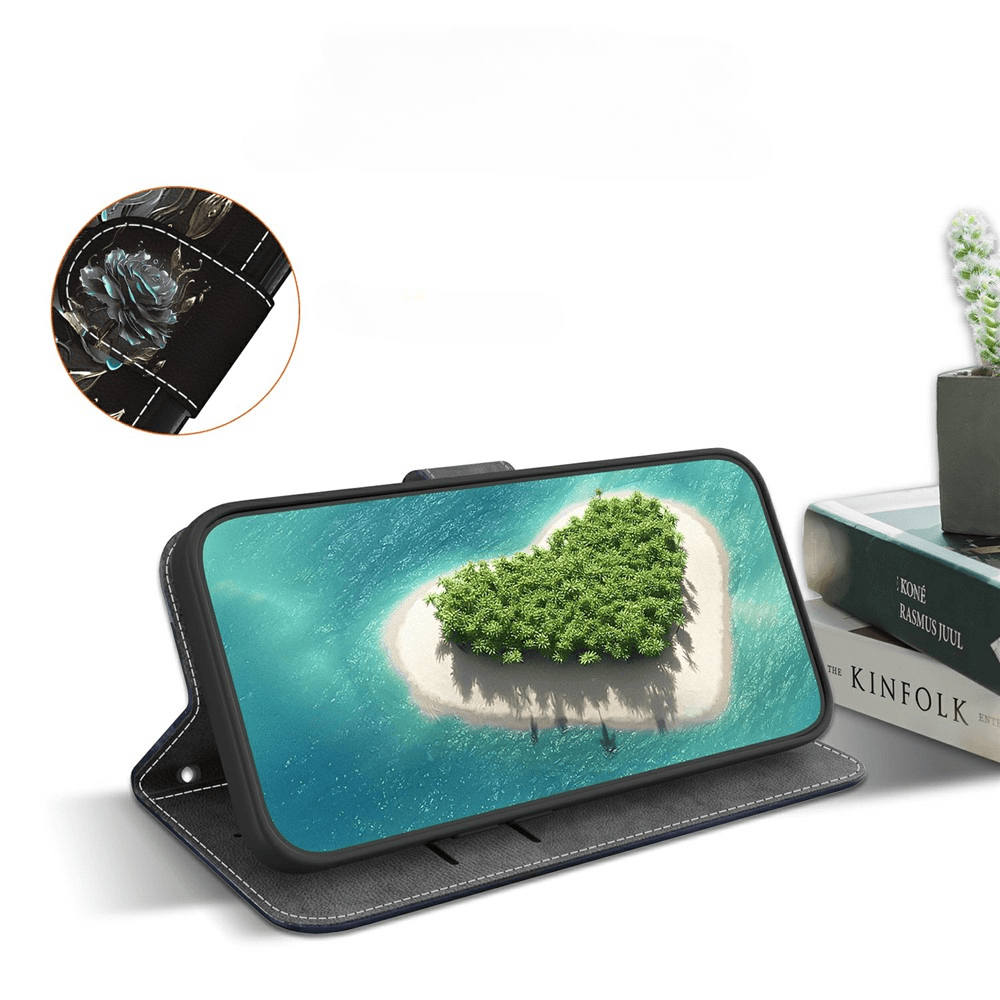 Smartphone in schwarzer Schutzhülle zeigt Herzinsel im Meer; Bücher und Kakteen im Hintergrund.
