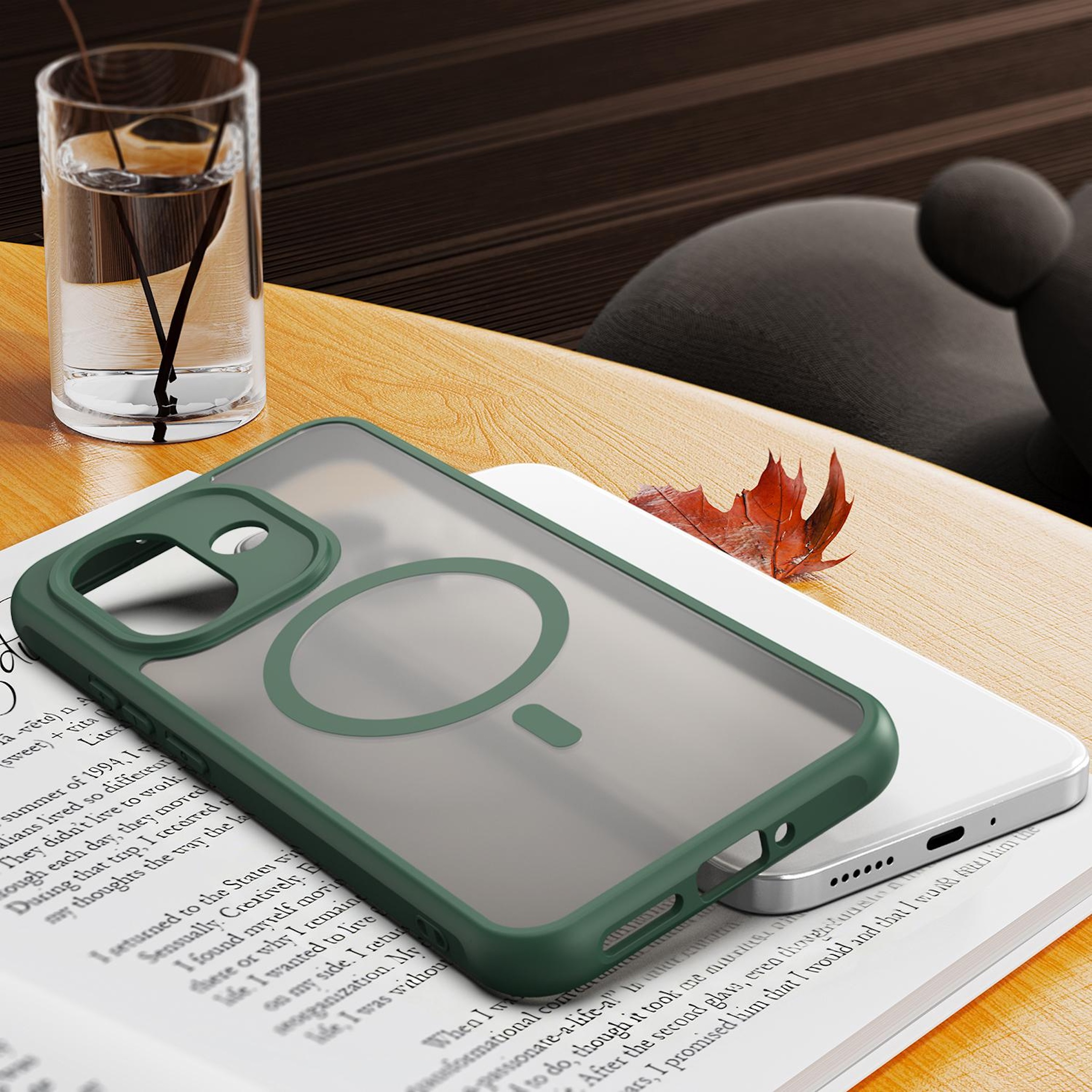 Grüne Handyhülle mit MagSafe-Ring auf einem Buch auf einem Holztisch, daneben ein Glas Wasser.