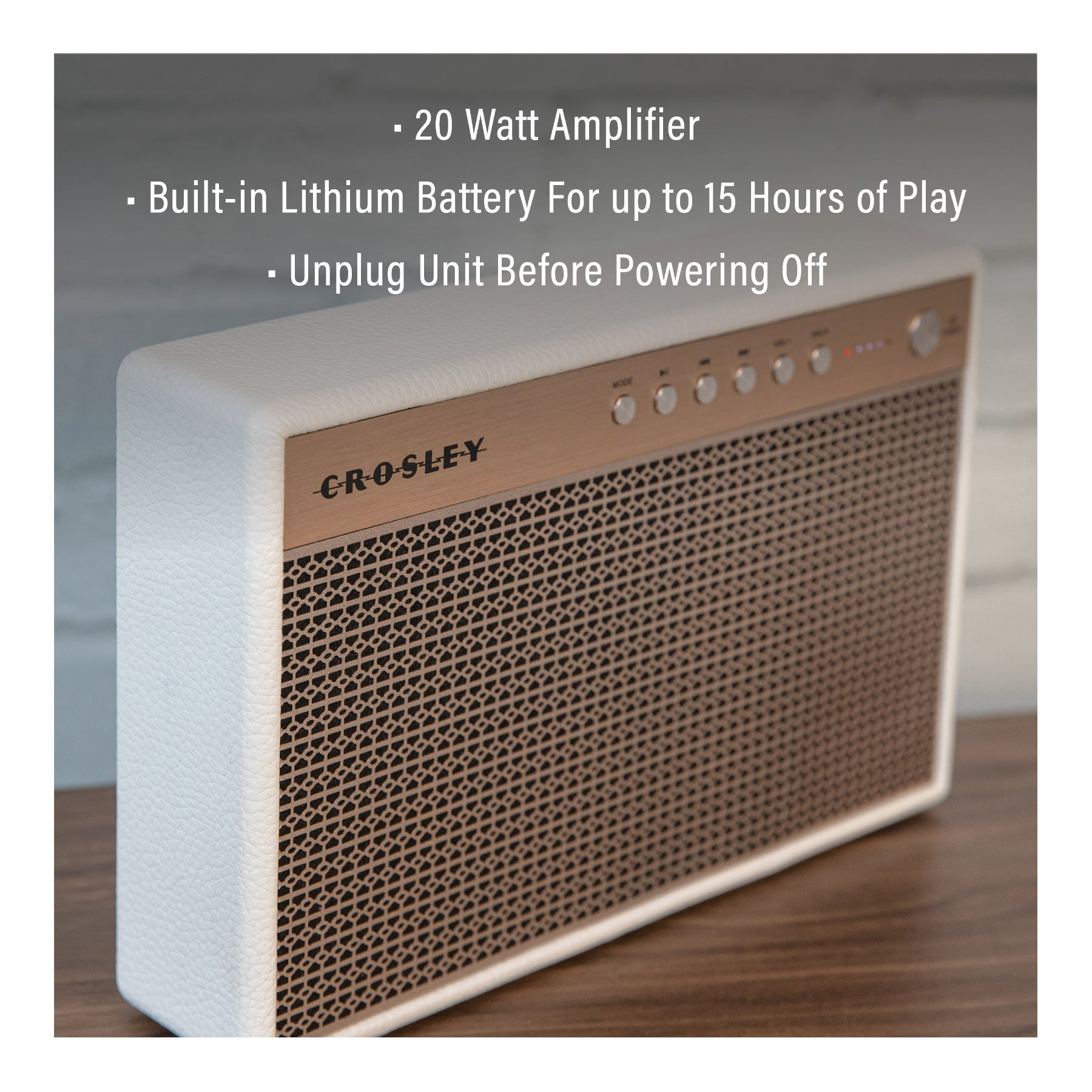 Ein weißer Crosley Bluetooth-Lautsprecher mit kupferfarbener Frontplatte steht auf einer Holzoberfläche.