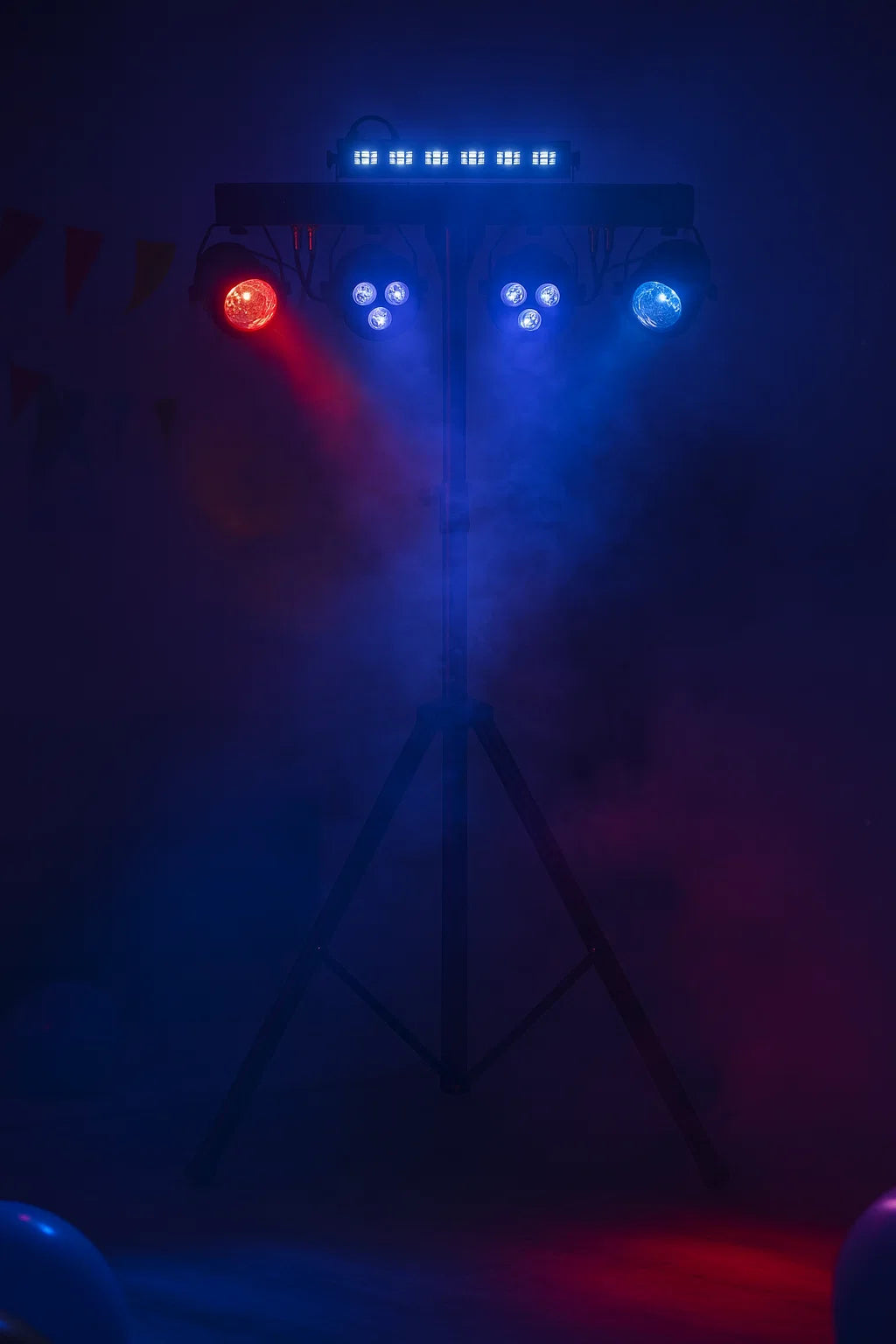Bühnenbeleuchtung auf einem Stativ in einer dunklen, rauchigen Umgebung mit roten und blauen Lichtkegeln.