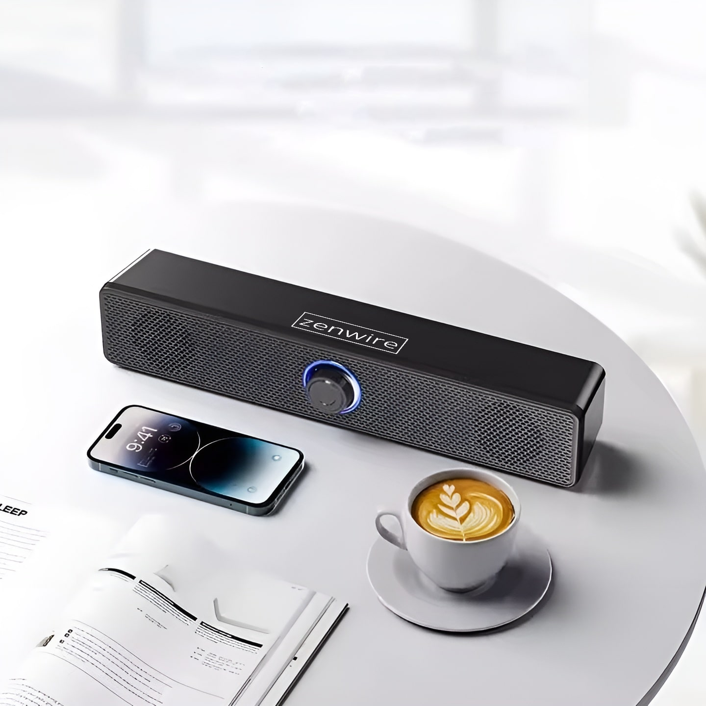 Una lunga soundbar, uno smartphone e una tazza di caffè sono su un tavolo chiaro.
