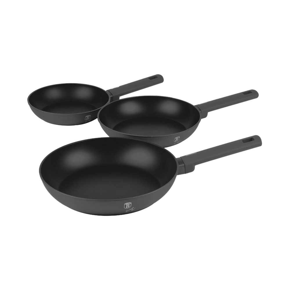 Trois poêles à frire noires de différentes tailles disposées en diagonale sur fond blanc.