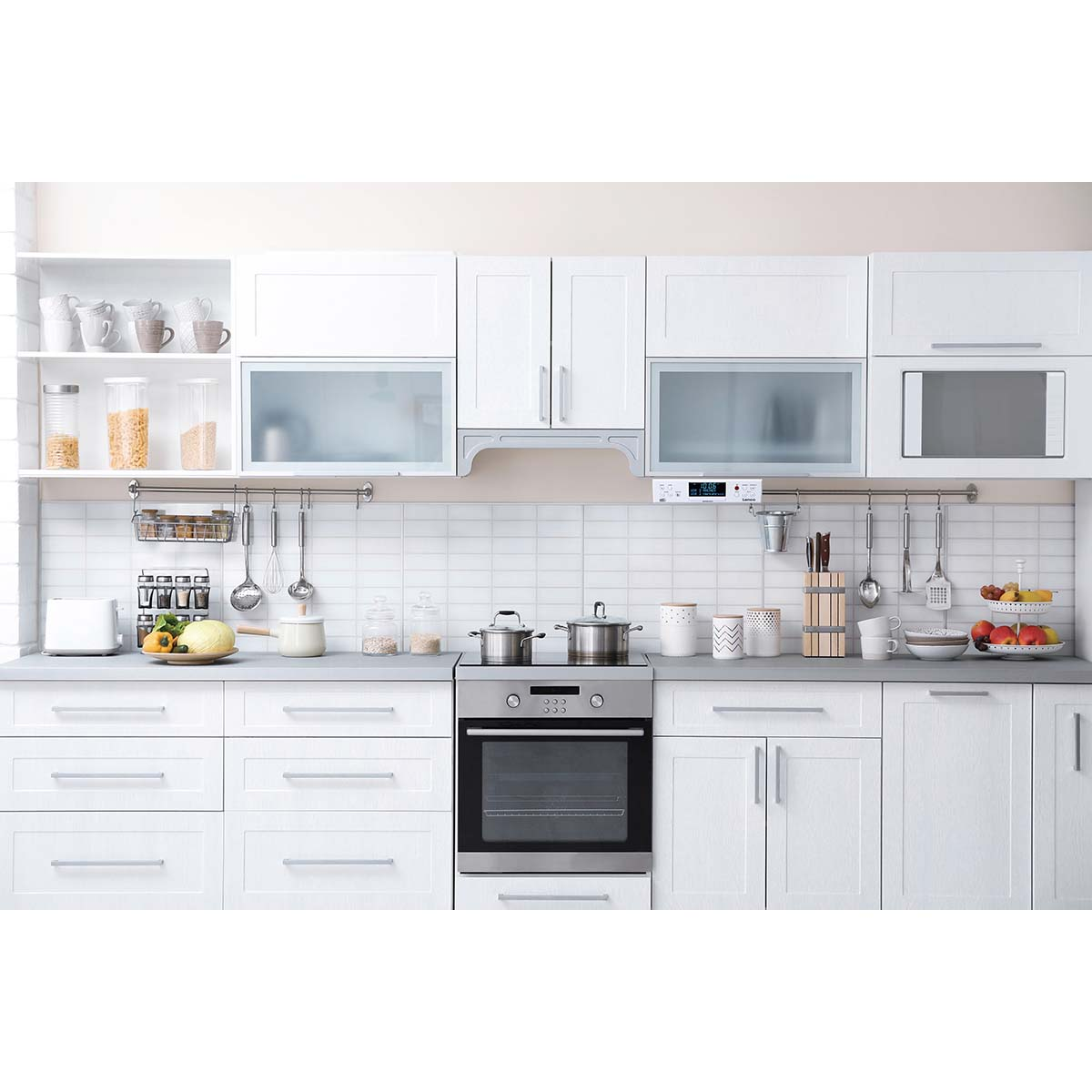 Una cucina moderna bianca con mobili bianchi, un piano cottura in acciaio inox e utensili appesi.