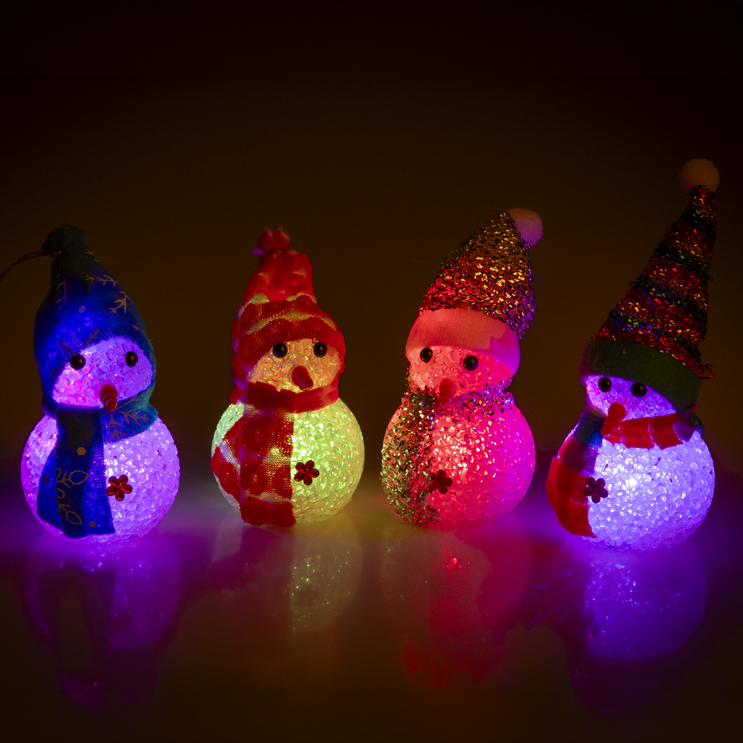 Quattro figure di pupazzi di neve luminose e colorate su sfondo scuro.