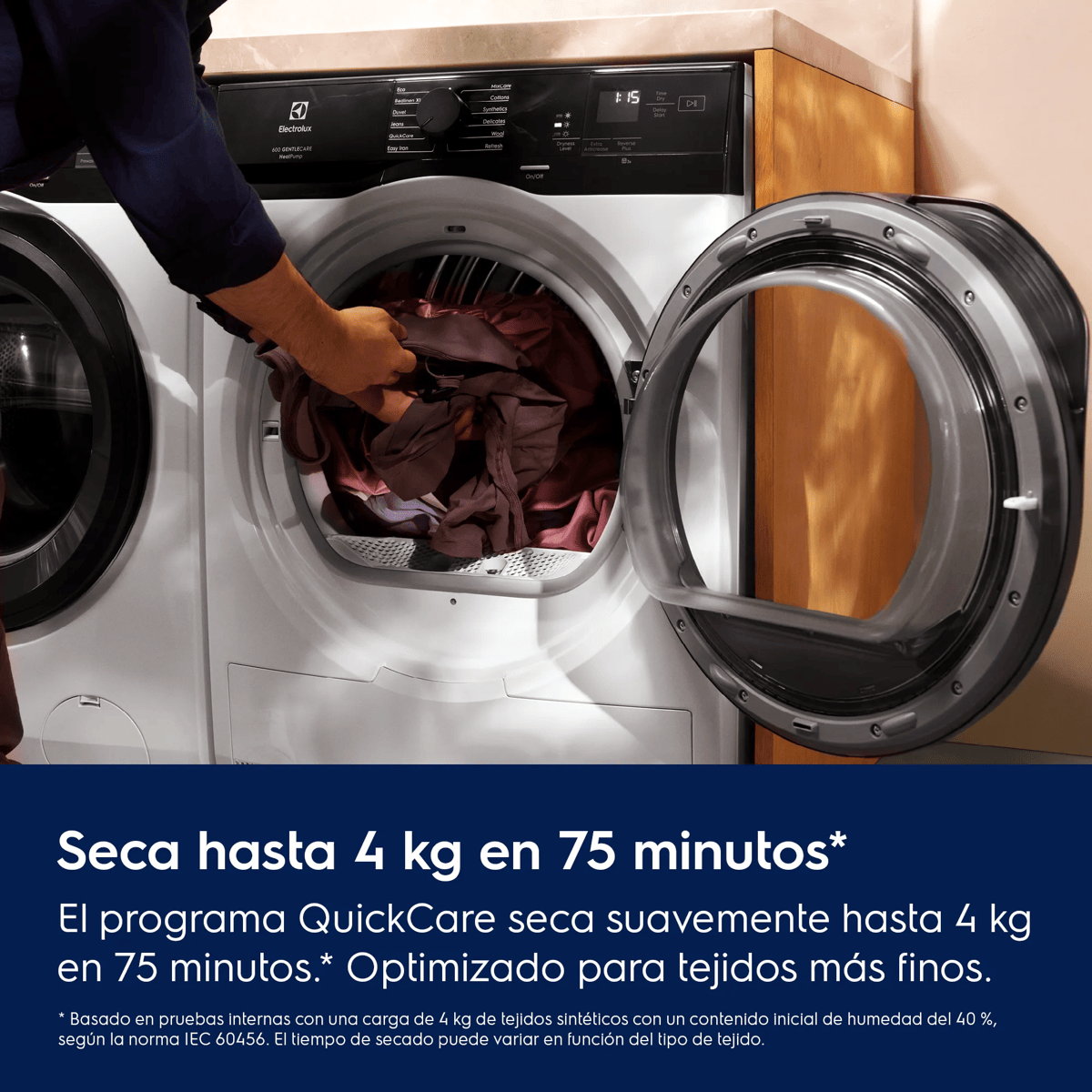 Una persona carga ropa en una secadora abierta de carga frontal.