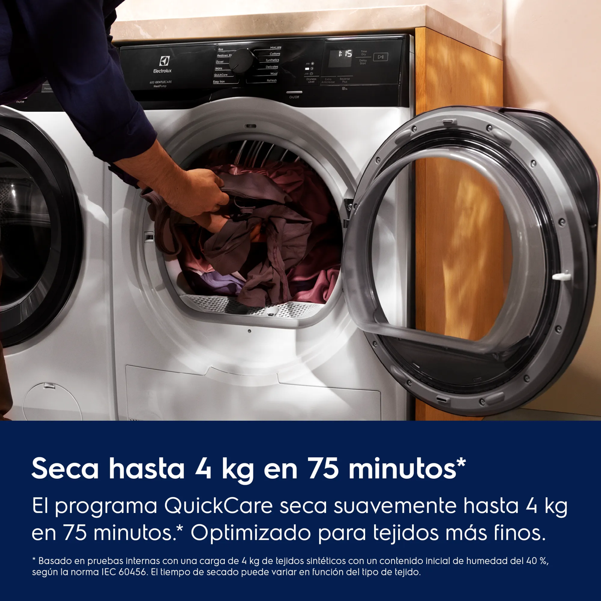 Una persona carga ropa en una secadora moderna de carga frontal.