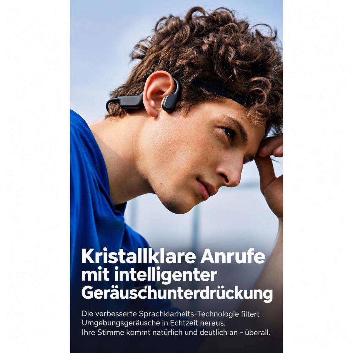 Ein junger Mann mit dunklen Locken und schwarzen Knochenschall-Kopfhörern schaut nachdenklich zur Seite.