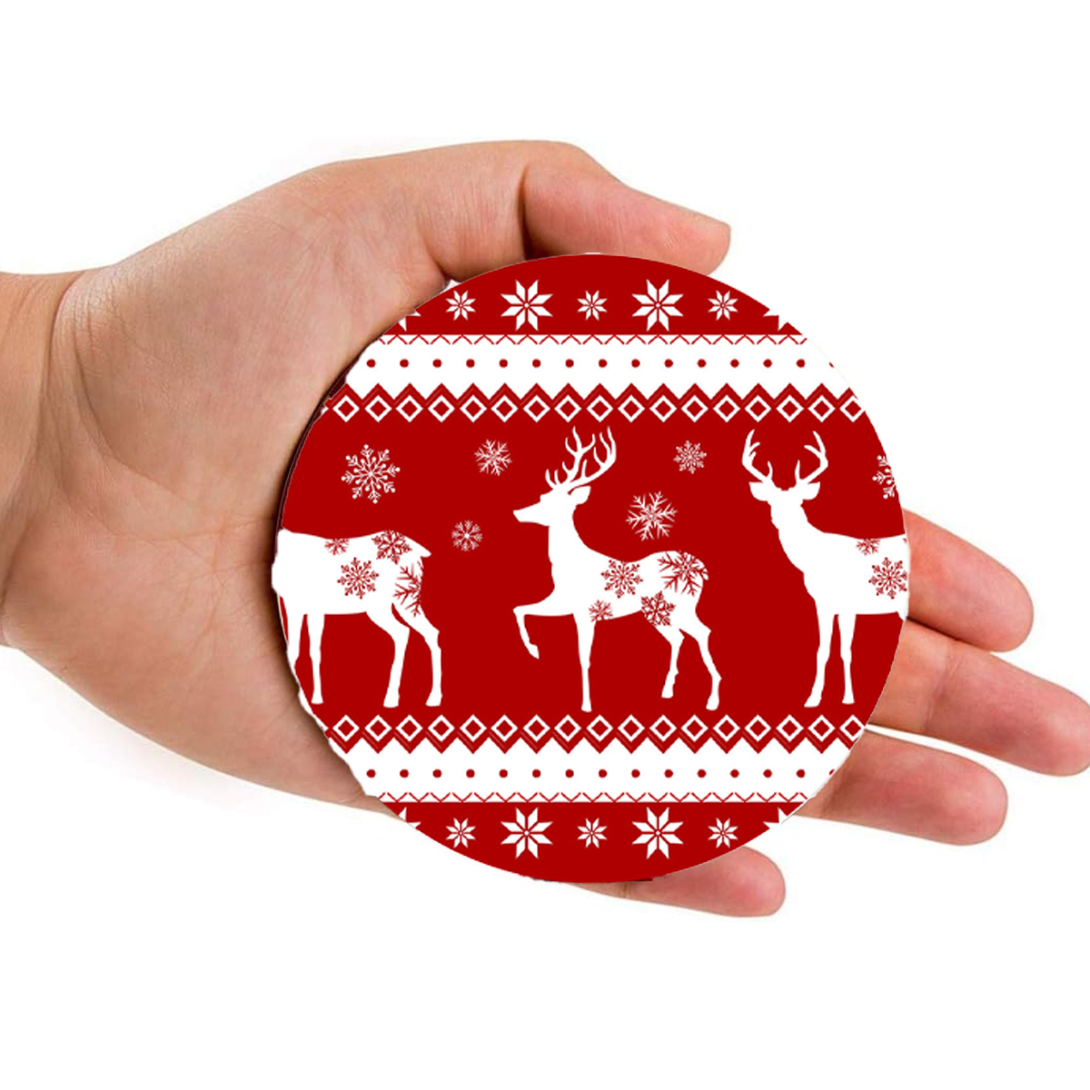 Eine Hand hält einen runden Untersetzer mit rotem Weihnachtsmotiv aus Rentiern und Schneeflocken.