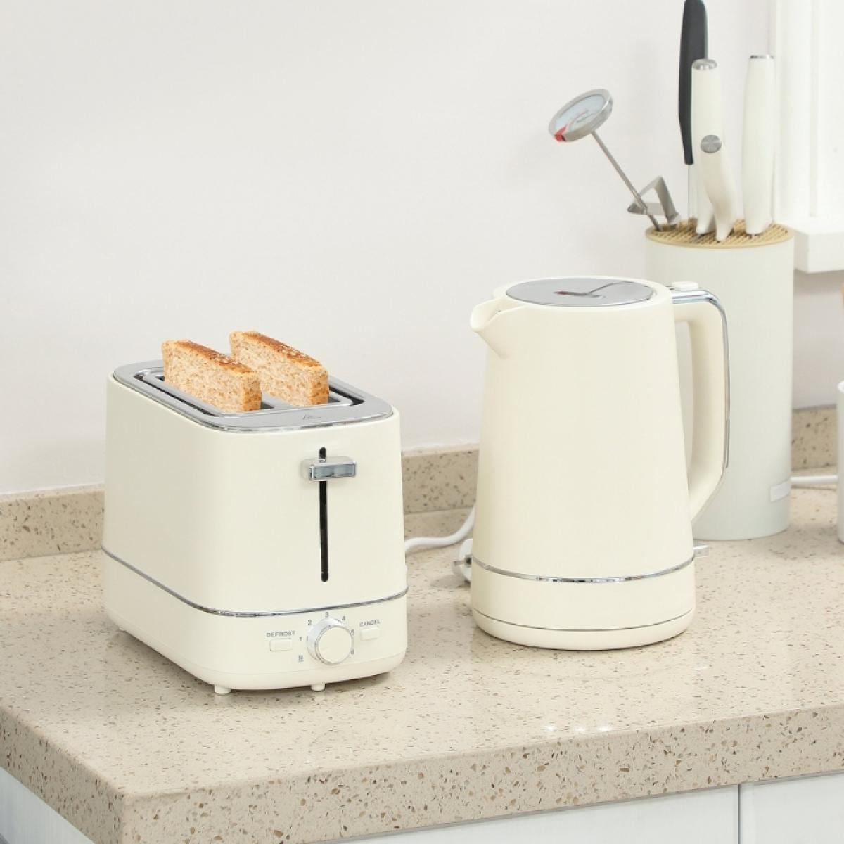 Ein beiger Toaster mit zwei Scheiben Brot und ein passender Wasserkocher stehen auf einer Arbeitsplatte.