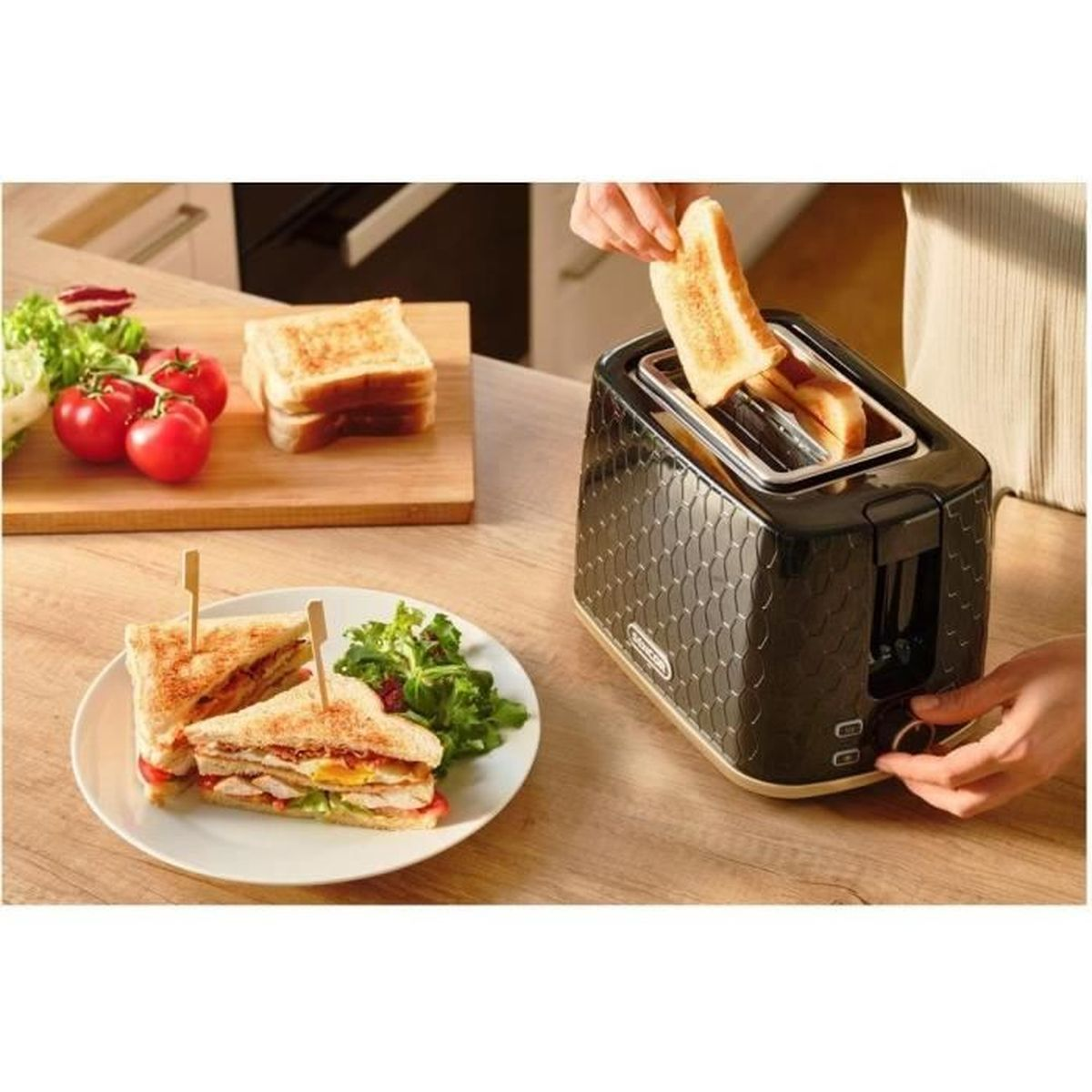 Persona che mette il toast in un tostapane nero accanto a un piatto di panini.