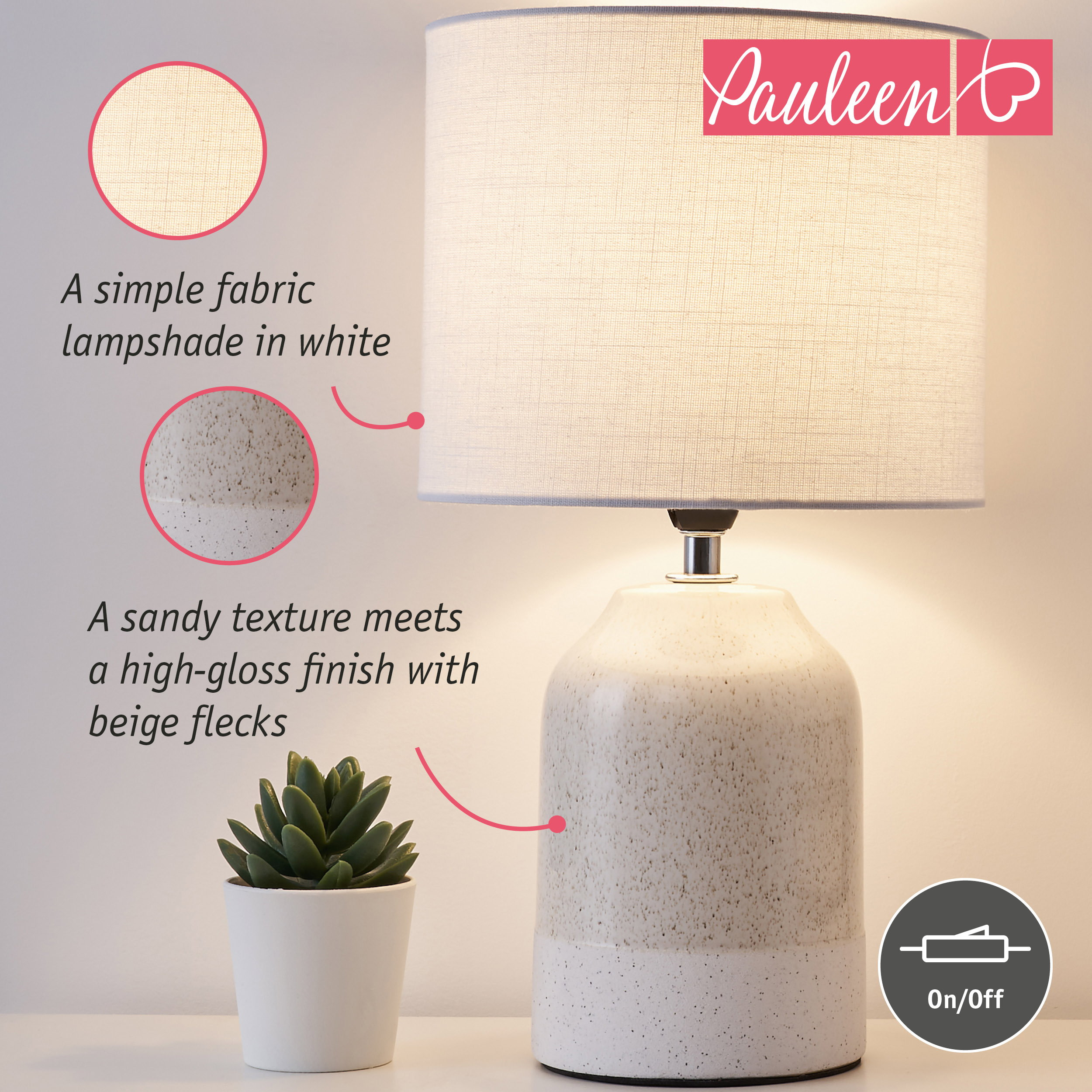 Una lampada beige maculata con paralume in tessuto bianco e una piccola pianta accanto.