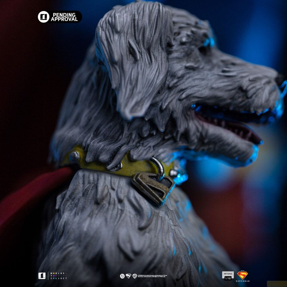 Primo piano di profilo di una statuetta di cane grigio peloso con collare borchiato giallo e mantello rosso, sfondo blu scuro.