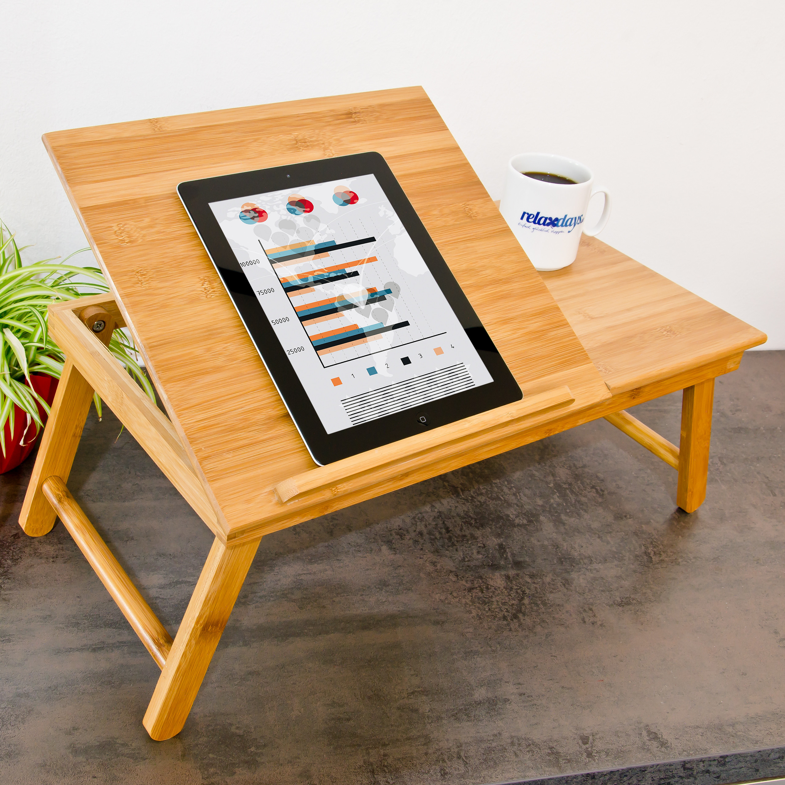 Ein Bambus-Betttisch auf einer grauen Oberfläche mit einem Tablet, das Grafiken zeigt, und einer weißen Tasse.