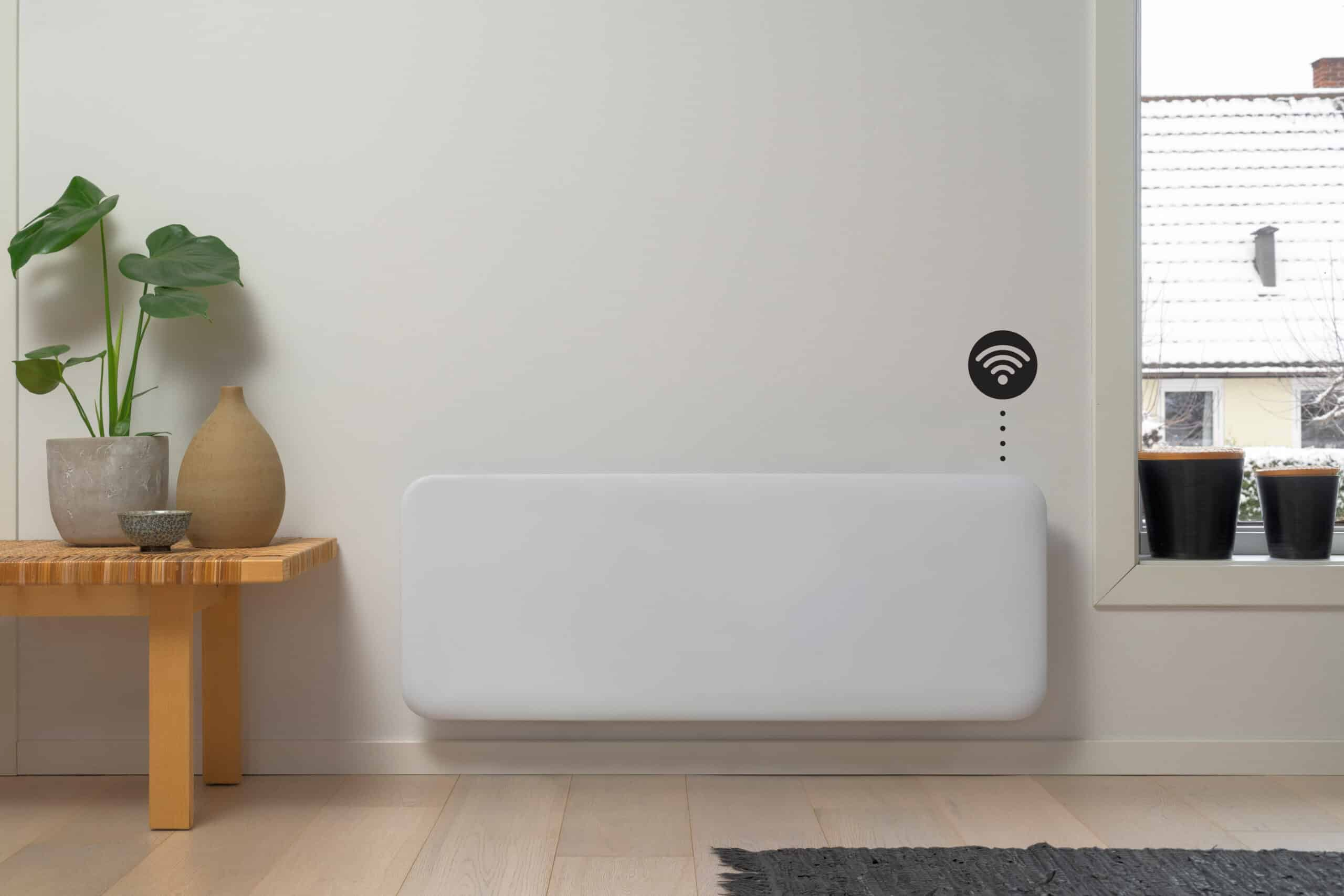 Un termosifone a pannello bianco è montato su una parete chiara sotto un'icona Wi-Fi, vicino a una pianta e a una finestra.