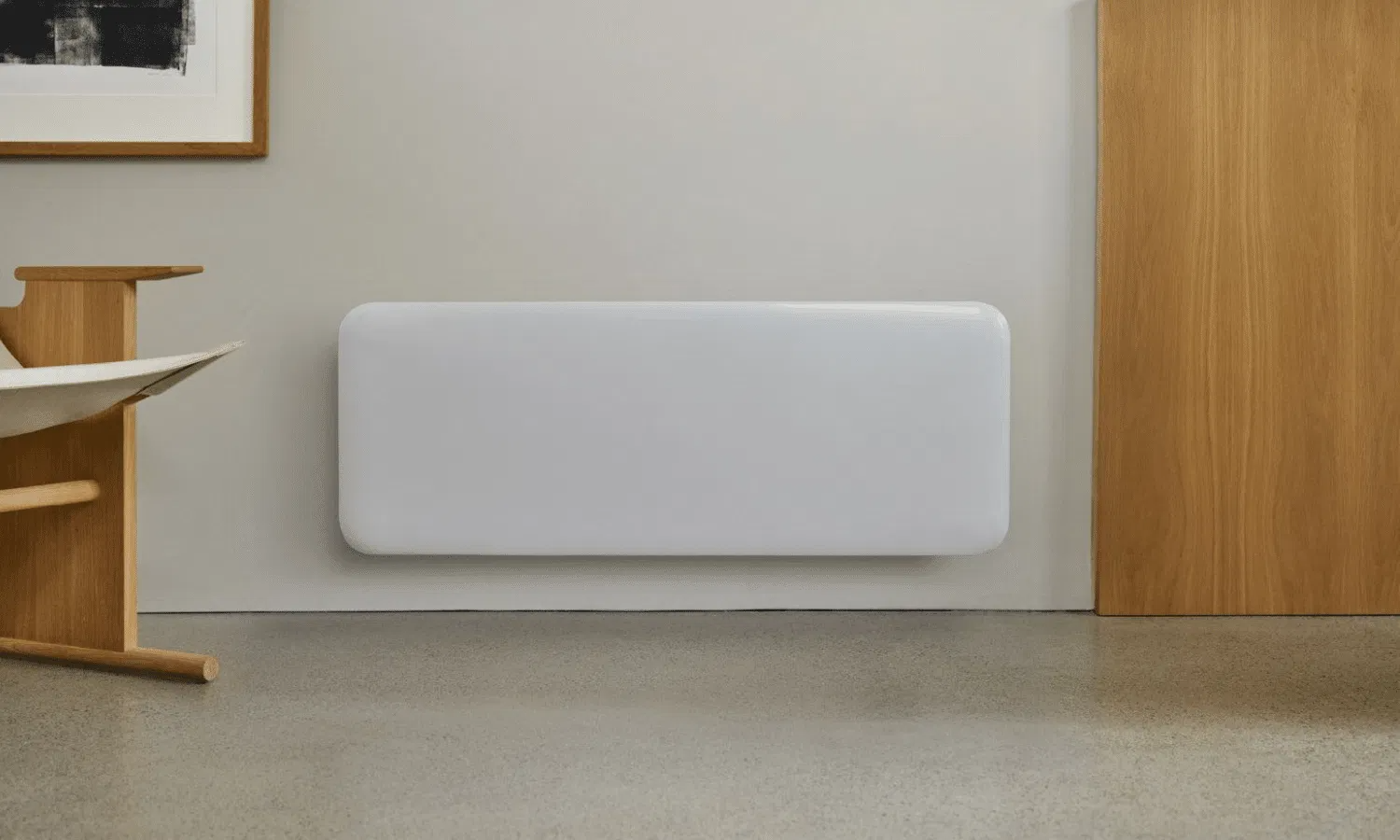 Un termosifone a pannello bianco e piatto è montato su una parete grigio chiaro, affiancato da elementi in legno.