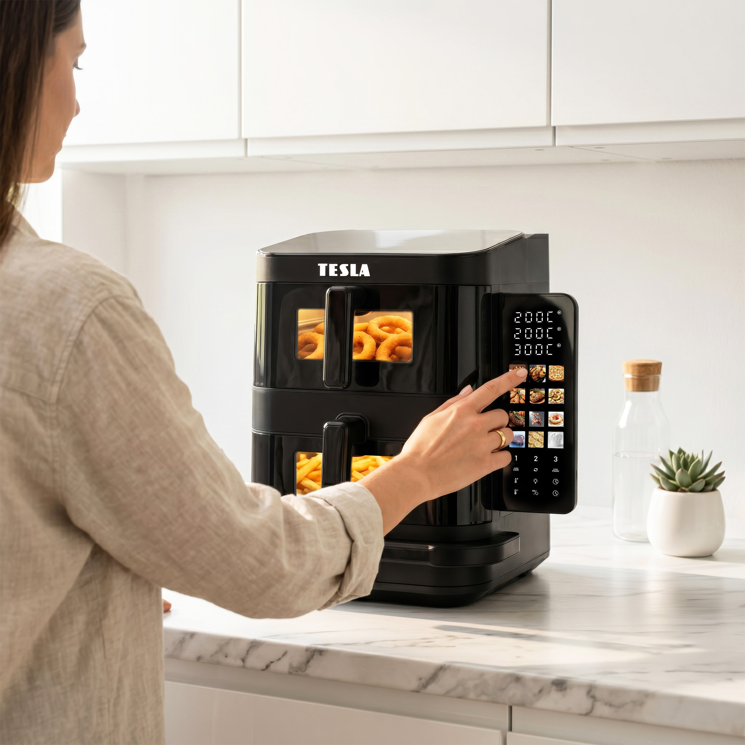 Una donna utilizza il touchscreen di una friggitrice ad aria Tesla nera in cucina.