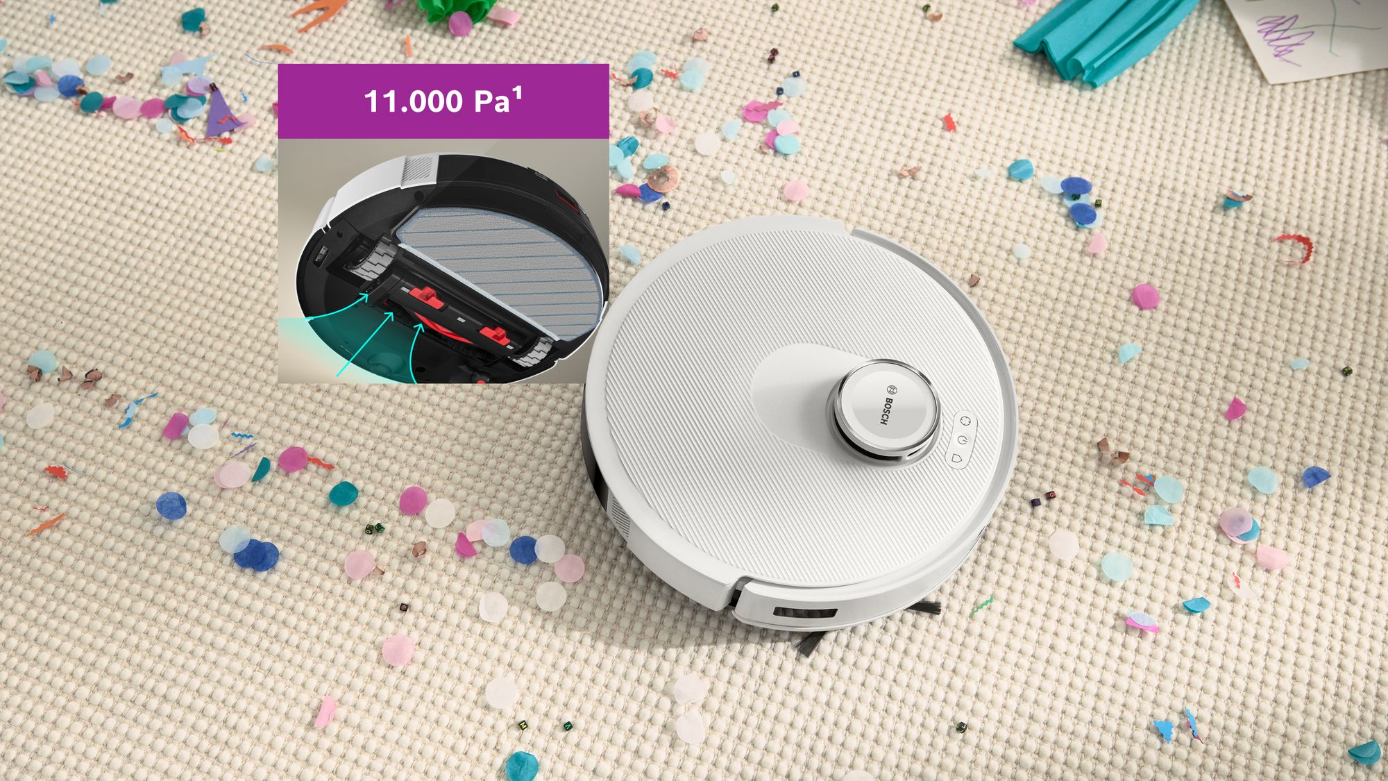 Un robot aspirateur blanc sur un tapis couvert de confettis, avec un encadré montrant le dessous et le texte 11 000 Pa.