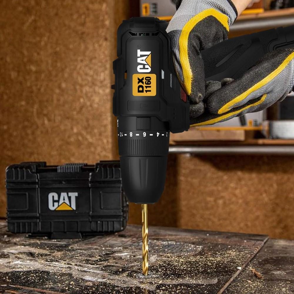 İş eldivenli bir kişi siyah Cat matkapla tezgahta delik açıyor, yanında çanta var.