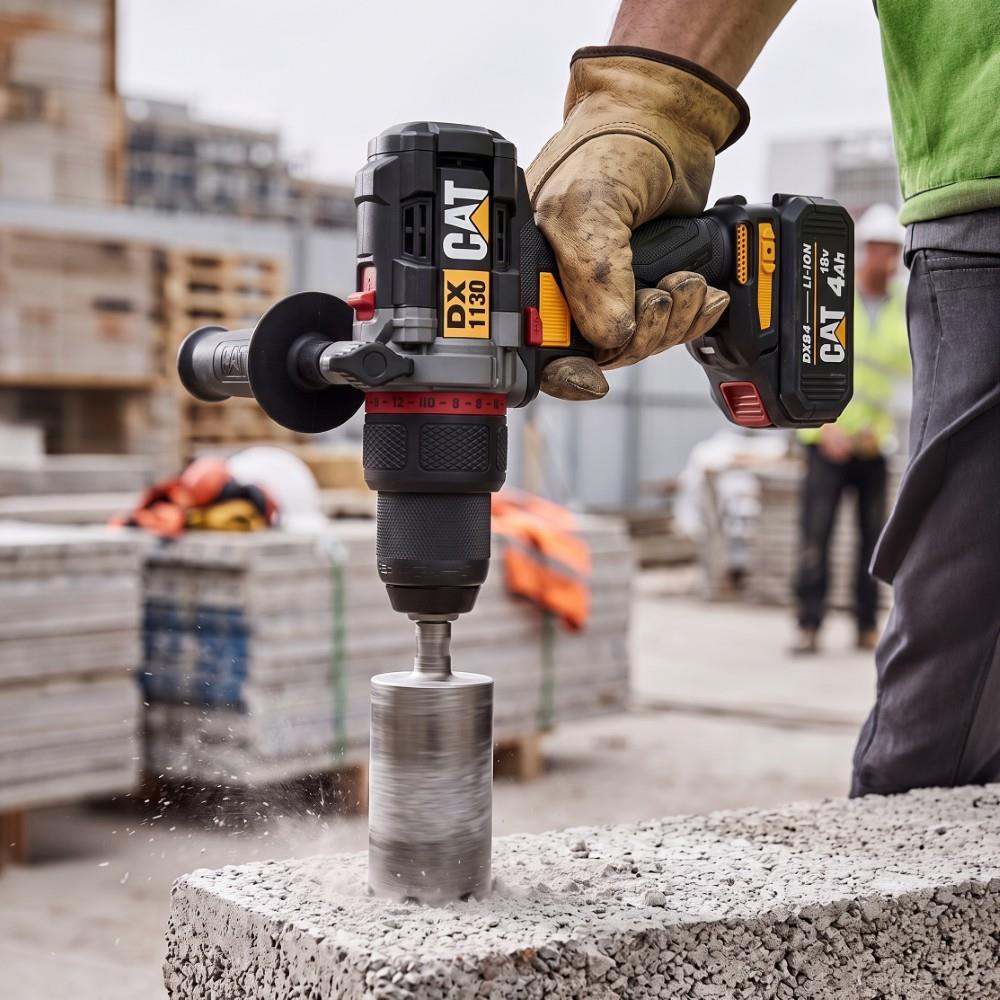Bir inşaat işçisi, şantiyede bir beton blok üzerinde CAT karot makinesi kullanıyor.
