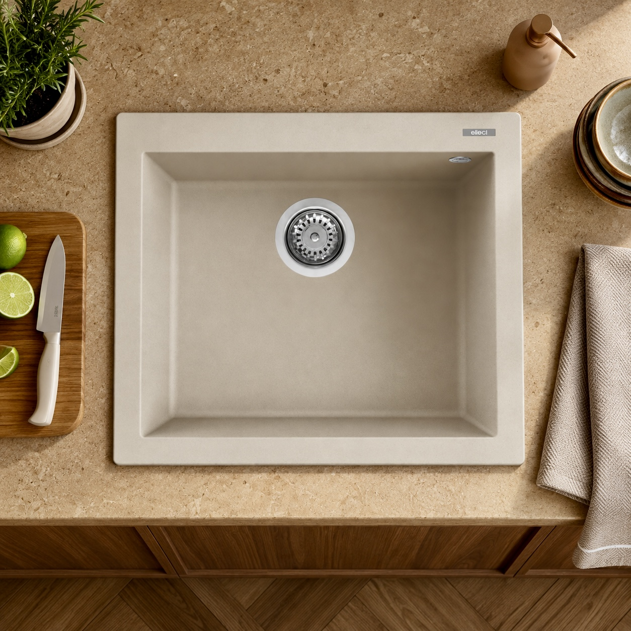 Lavello da cucina beige su piano di lavoro chiaro con lime, coltello e strofinaccio.