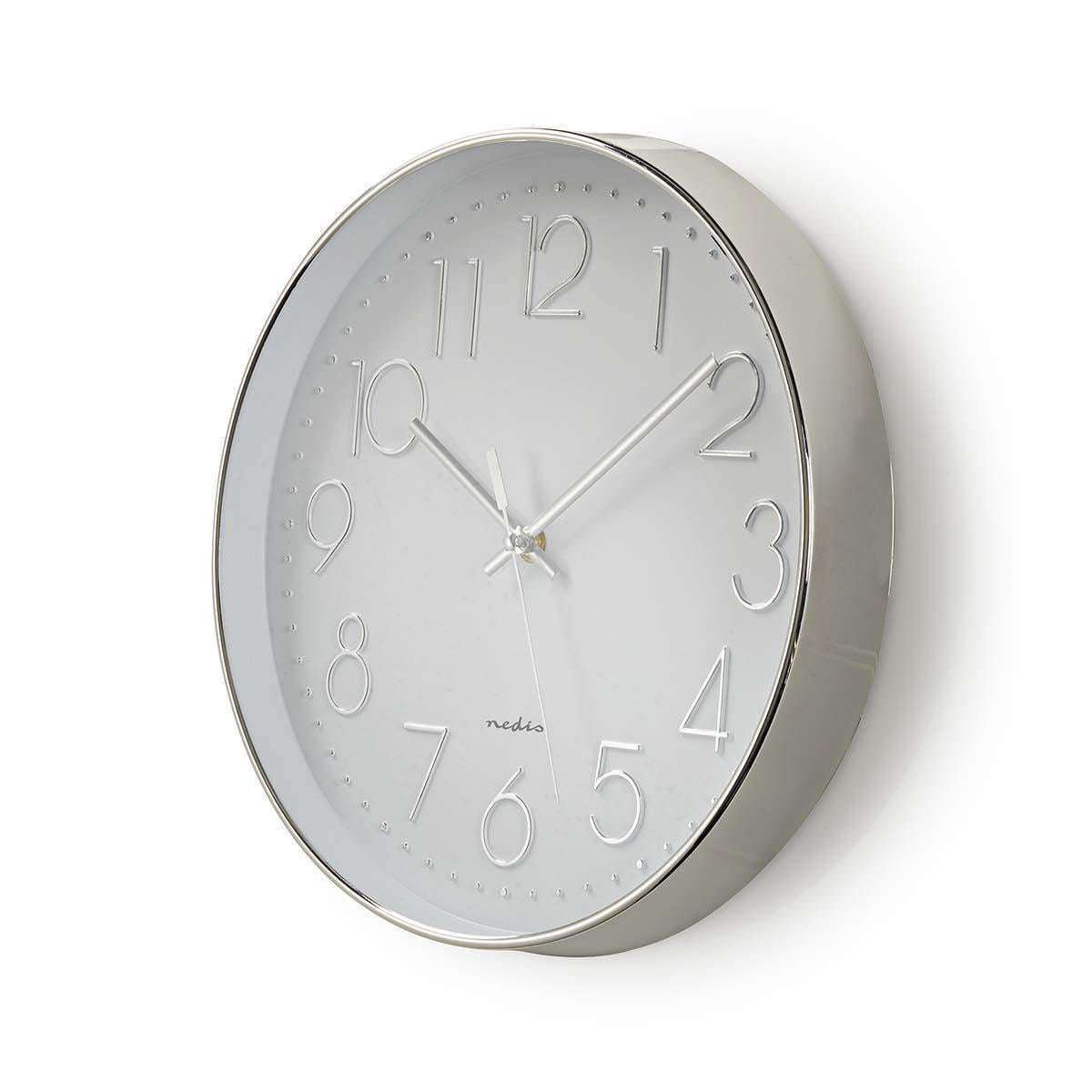 Eine silberne Wanduhr mit erhabenen Zahlen und weißem Zifferblatt auf hellem Hintergrund.