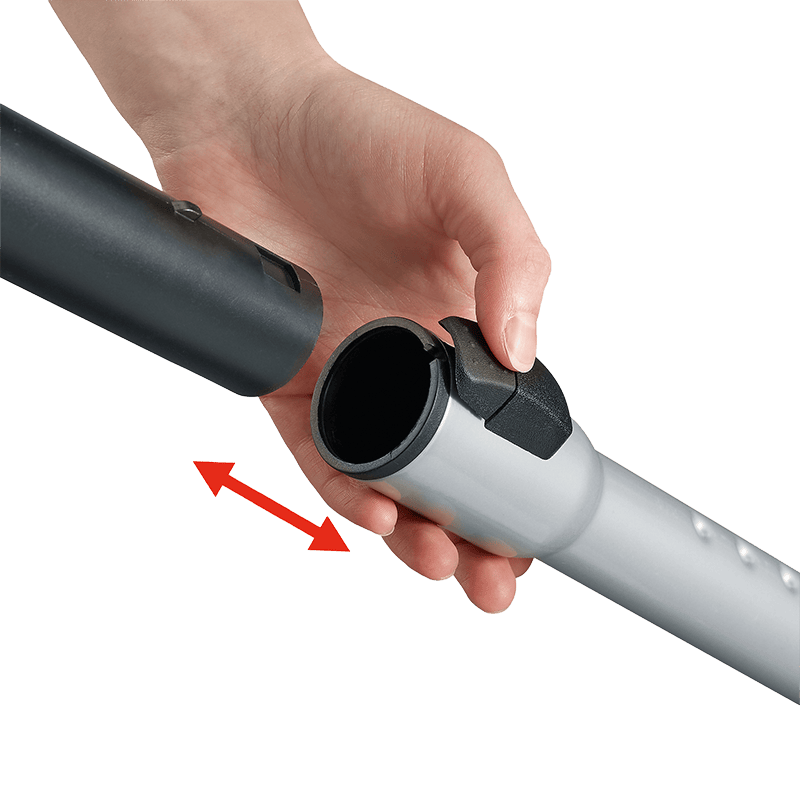 Una mano conecta dos piezas de un tubo de aspiradora sobre un fondo negro.