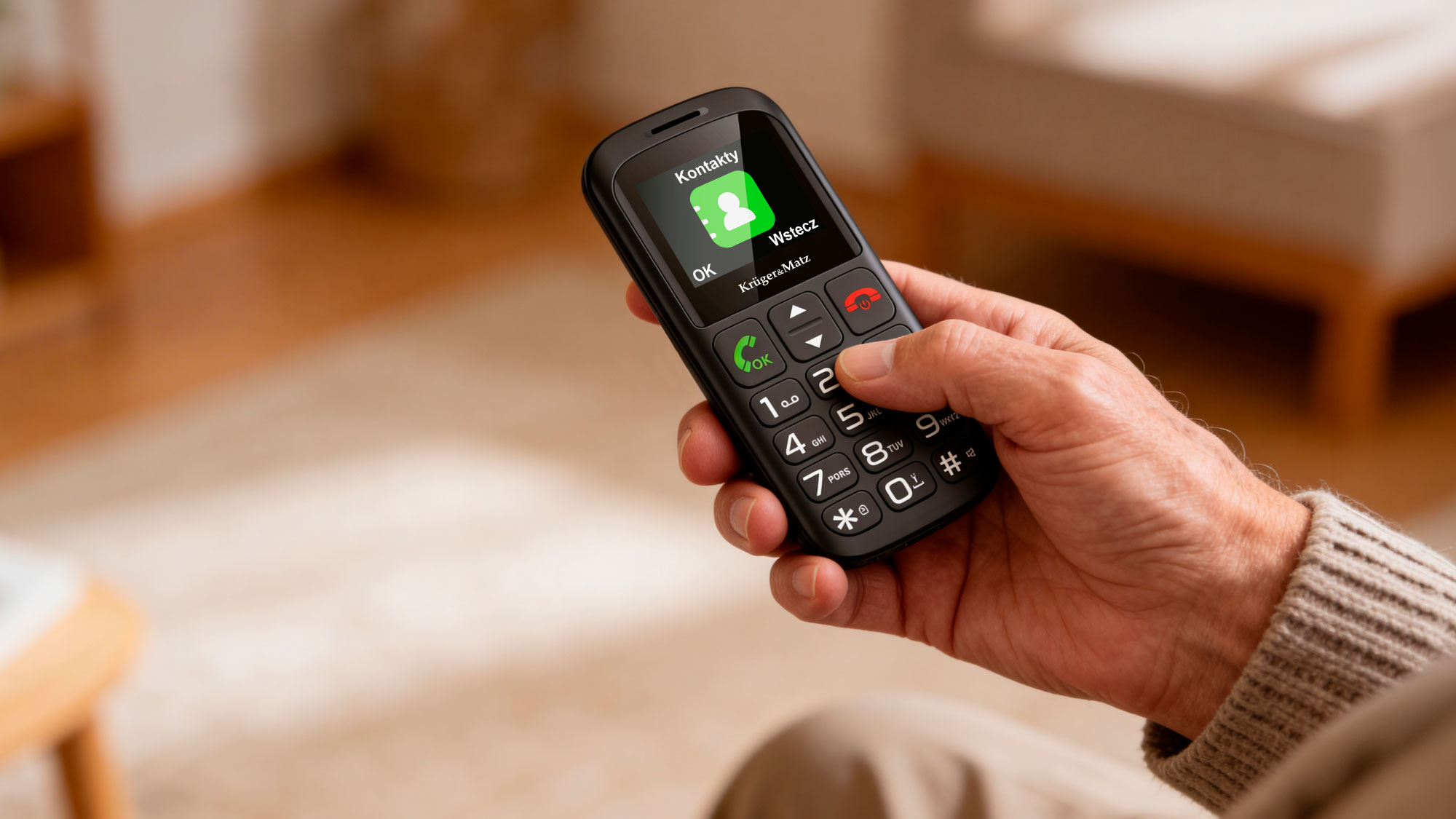 Dłoń trzyma prosty czarny telefon z zieloną ikoną kontaktów na ekranie.