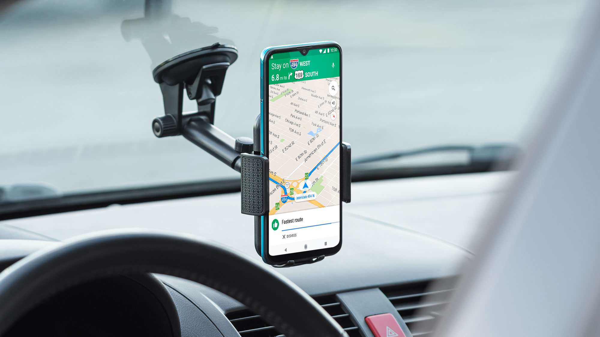Smartfon w uchwycie samochodowym wyświetla mapę nawigacji na ekranie.